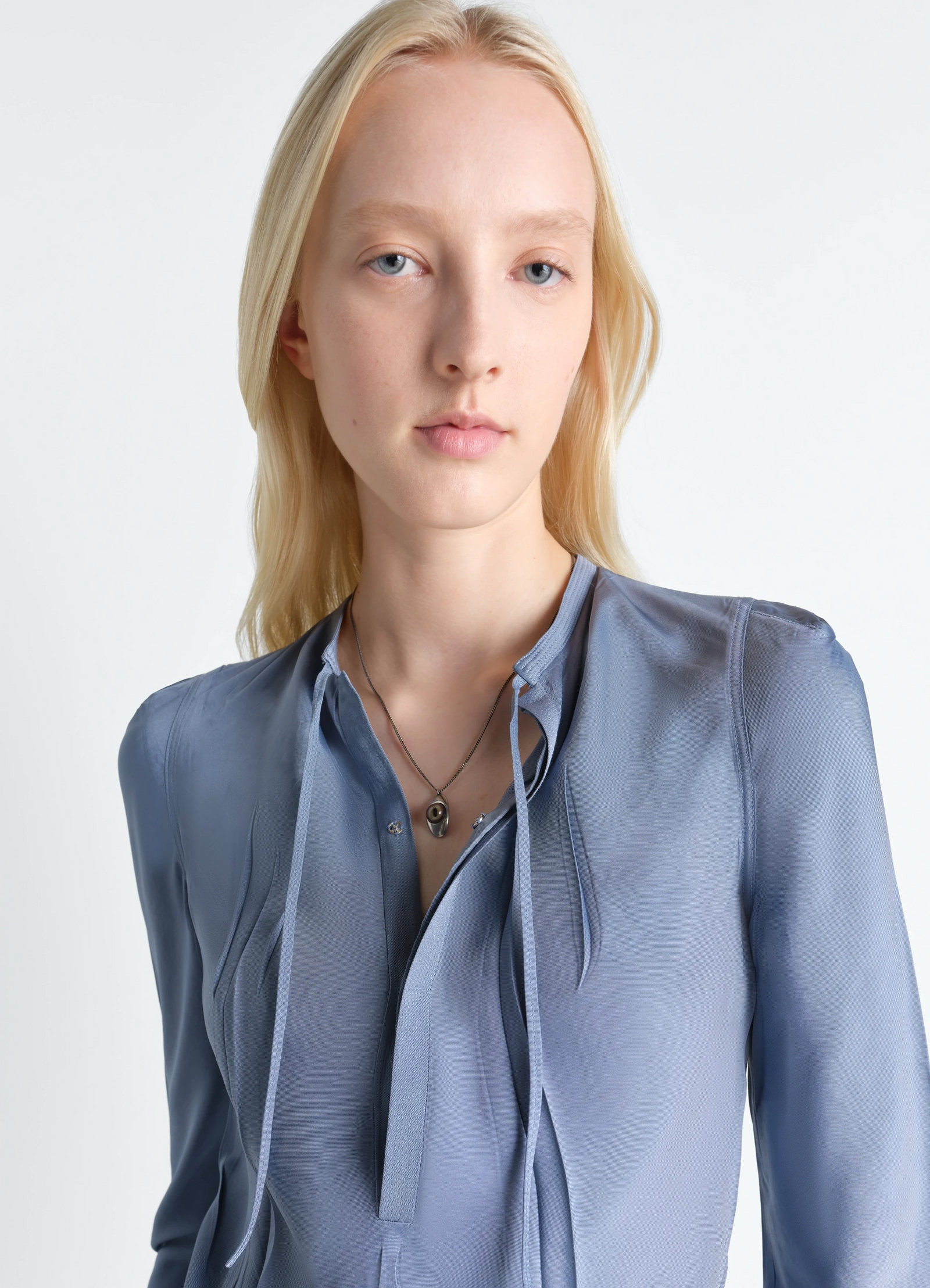 Cat eye pendant necklace in silver-plated brass, model shot, worn detail view layered over clothing