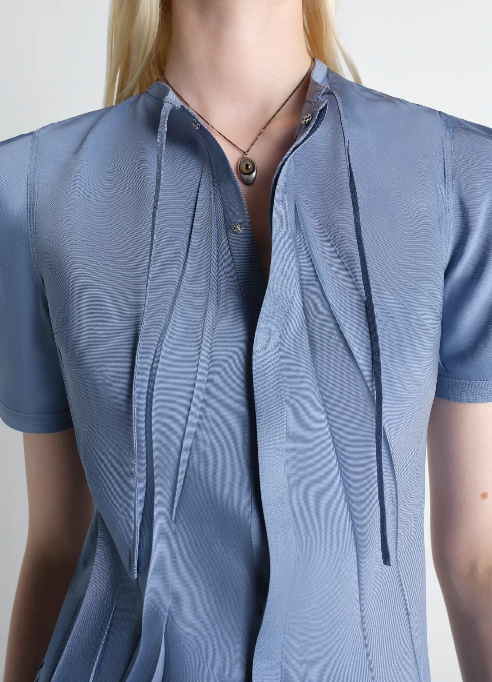 Cat eye pendant necklace in silver-plated brass, model shot, close-up view draped over buttoned blouse