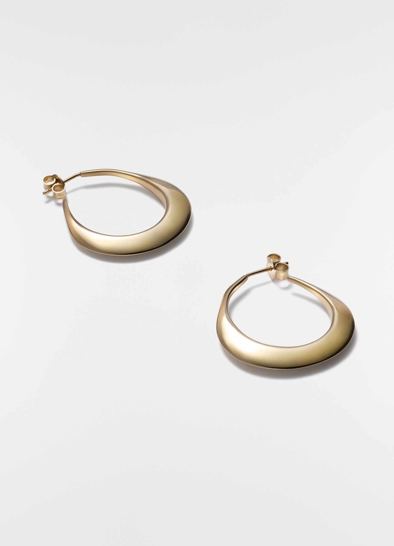 Drop hoop earrings in gold vermeil metal by lemaire styled on white background close-up detail
