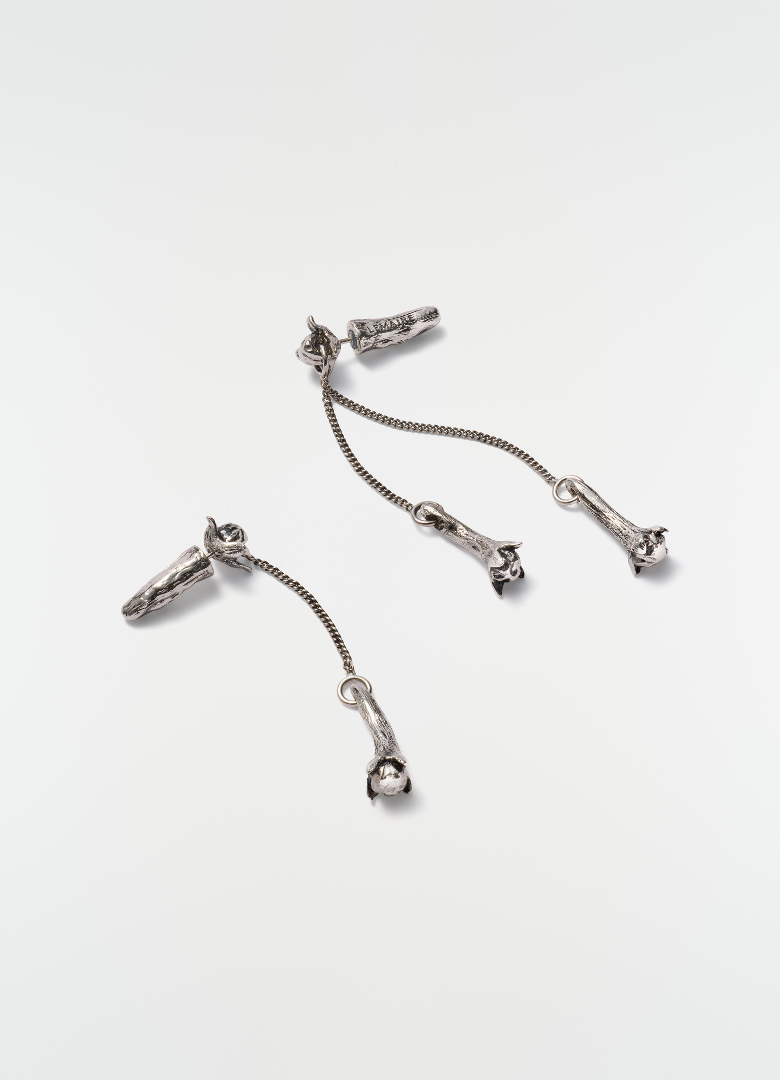 Clove pendant silver earrings by lemaire with chain links laid flat on white background close-up detail