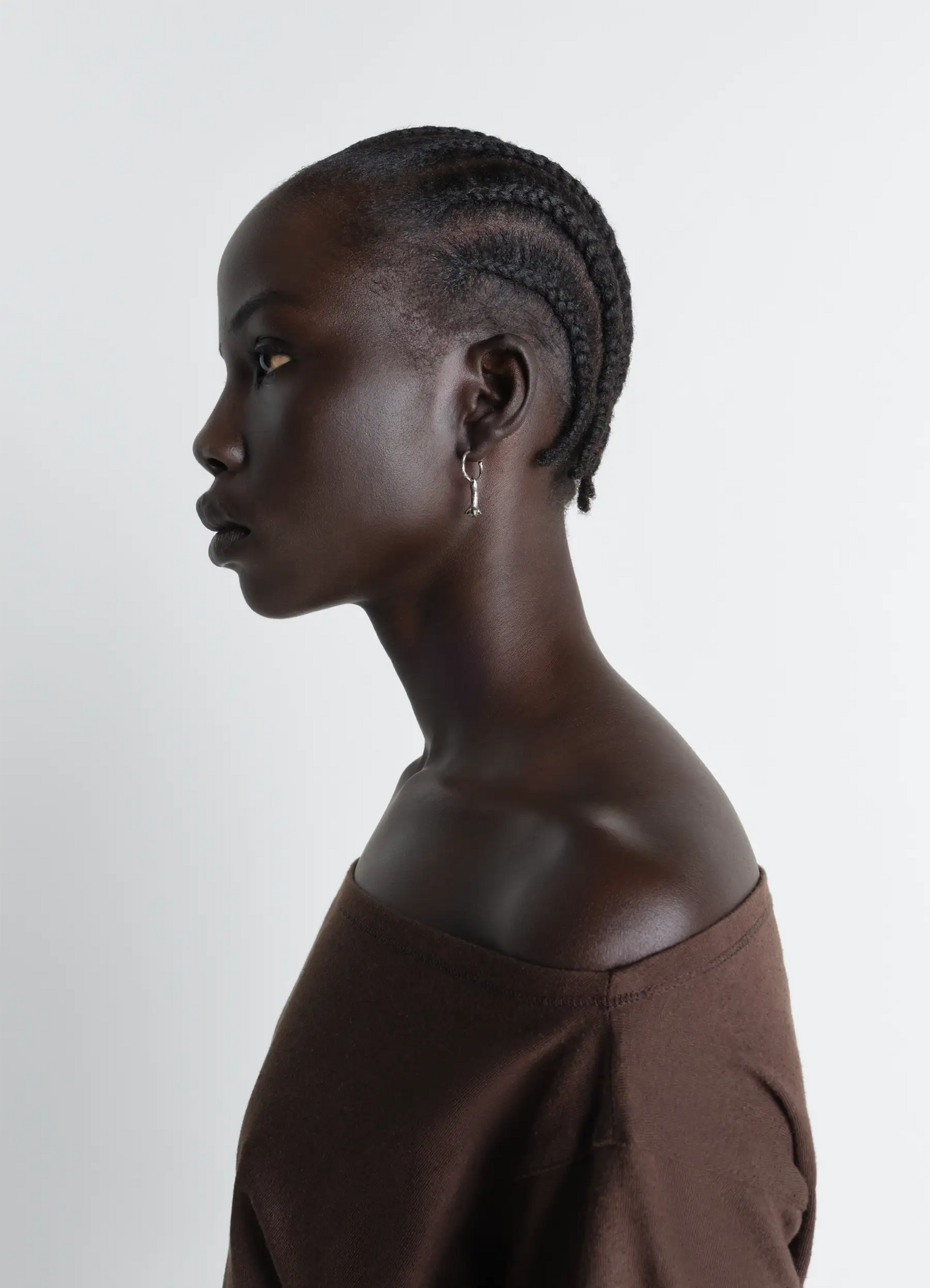 Clove earrings in hammered patinated brass, model shot, left profile view single clove dangle