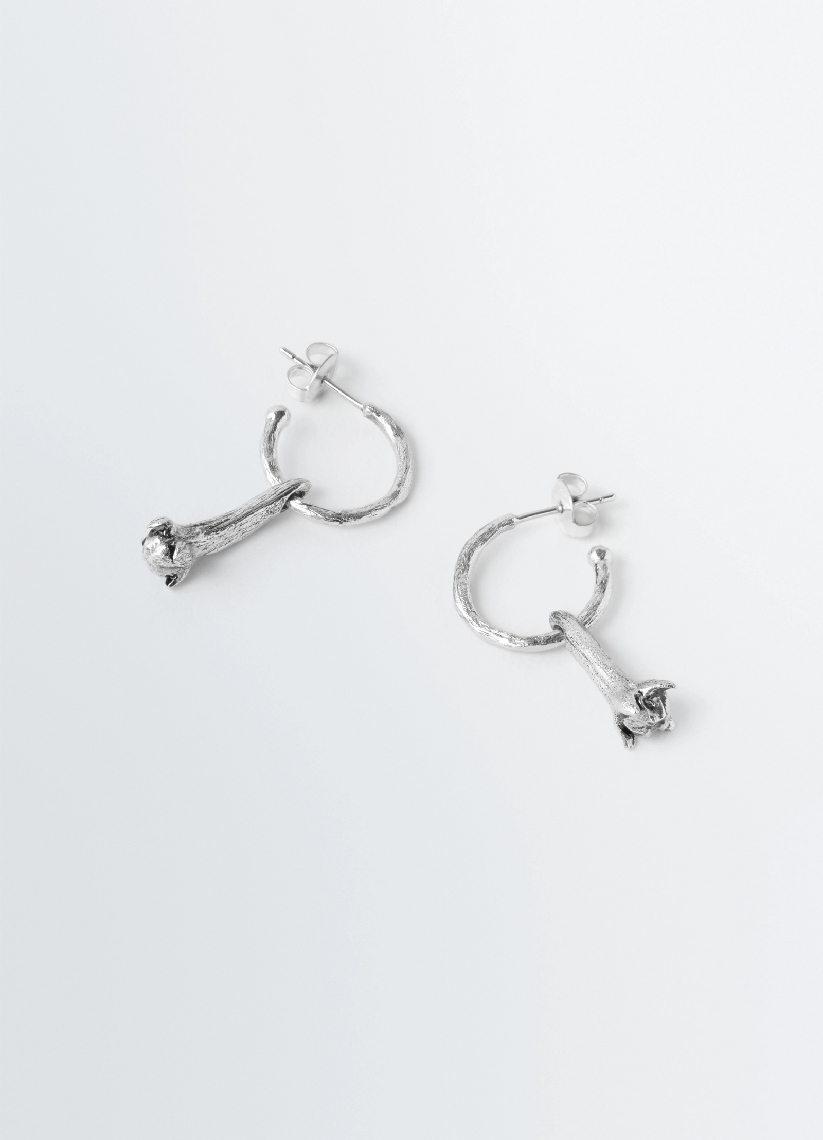 Clove earrings in hammered patinated brass, product shot, overhead angle textured hoops
