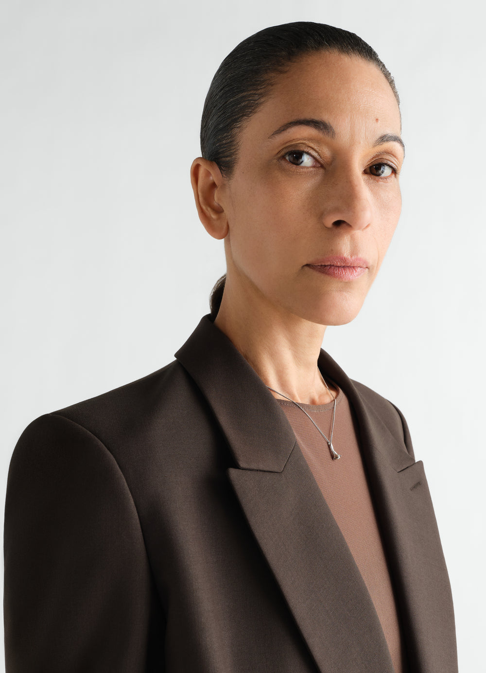 Clove silver necklace by LEMAIRE worn by model with brown blazer front close-up detail