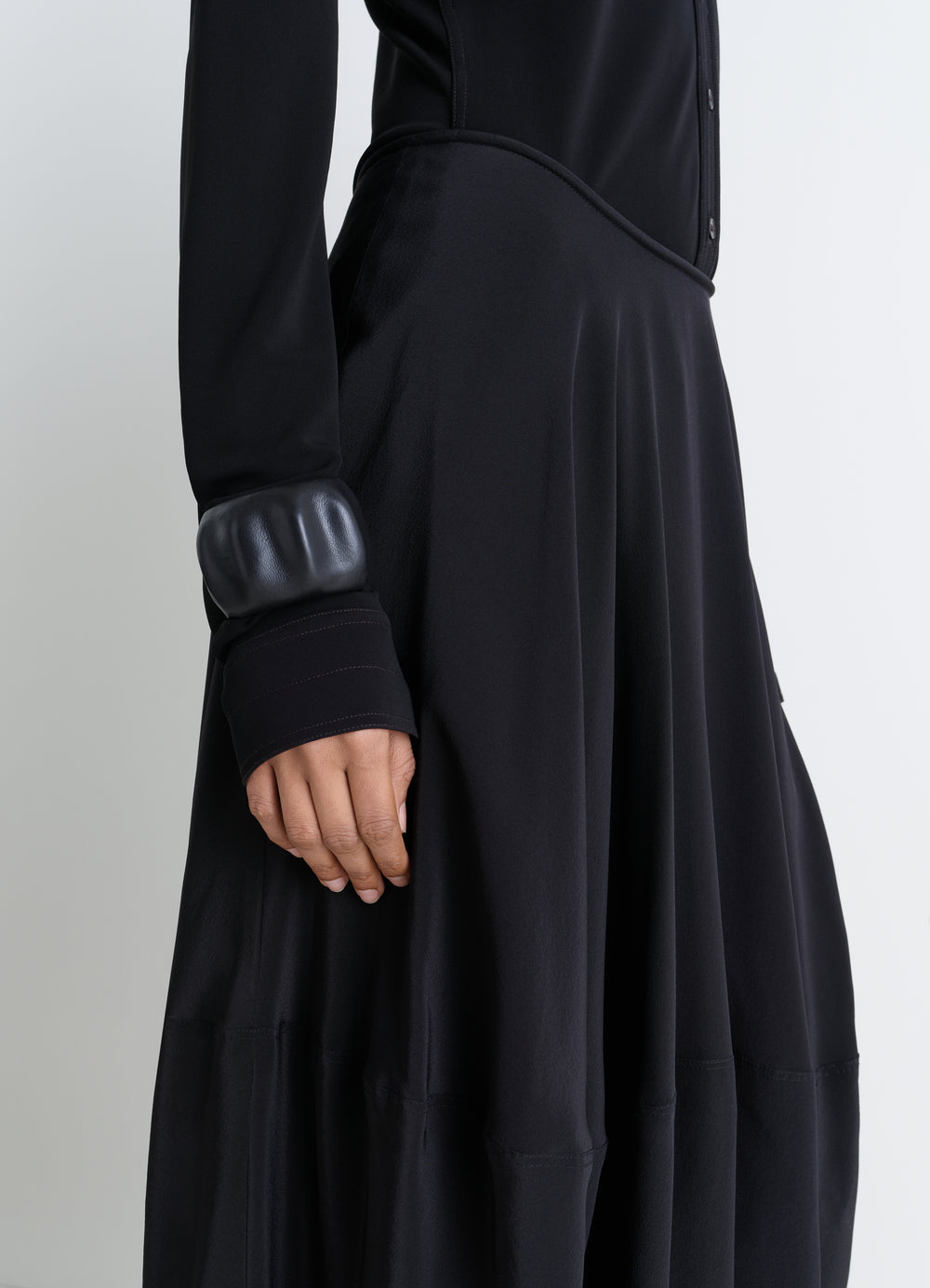 Carlos black leather cuff worn by a model with LEMAIRE black dress, close-up detail of sleeve and skirt