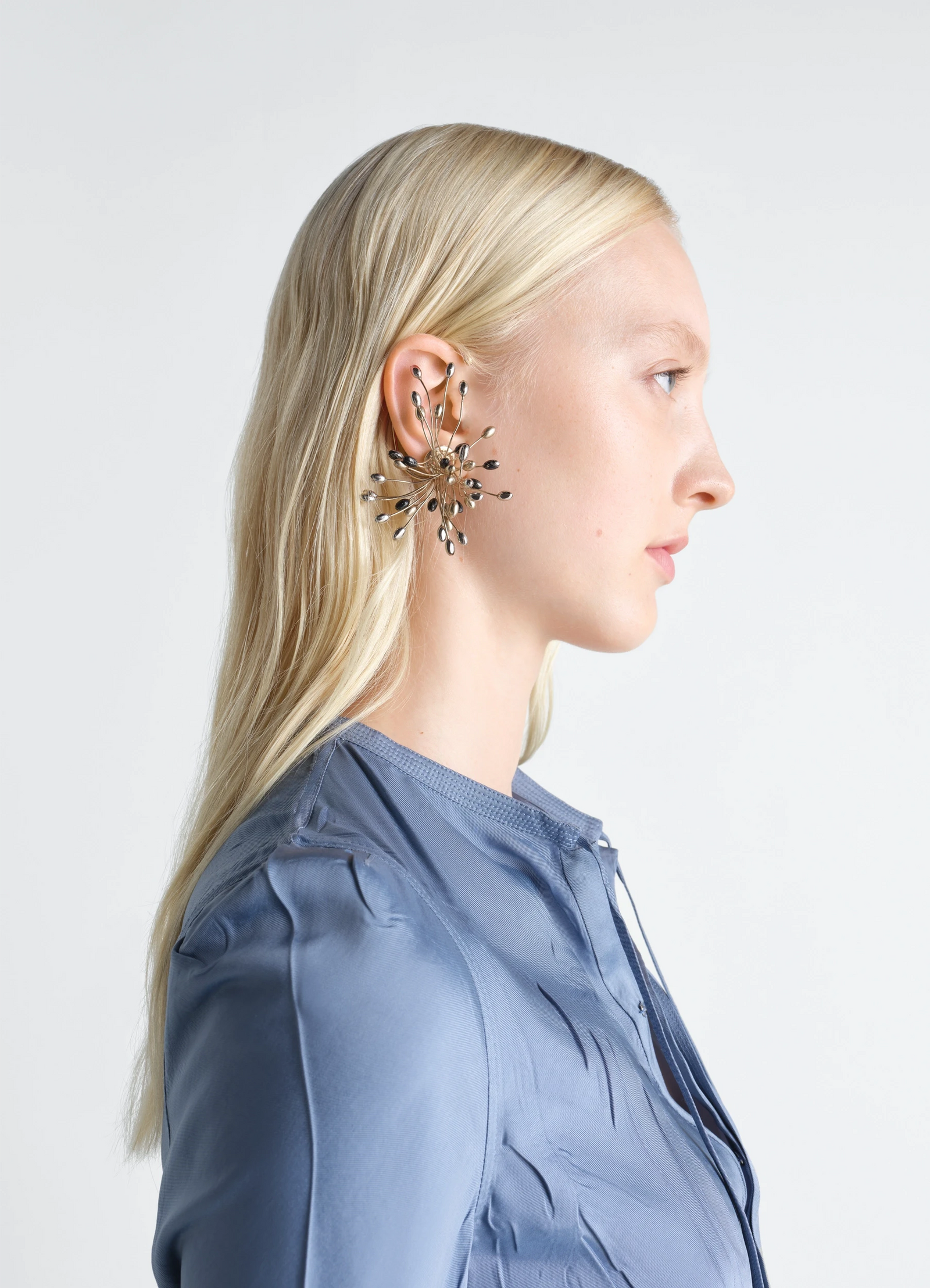 Seeds single earring in varied galvanic treatments, model shot, side view floral burst design