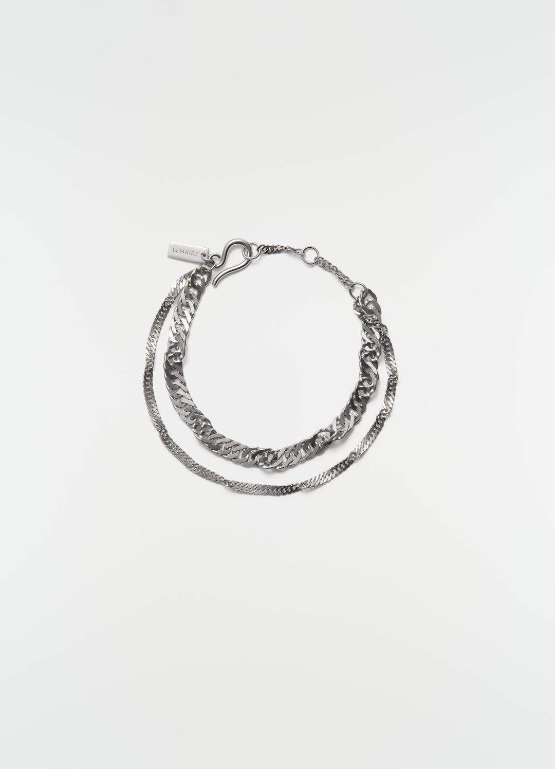 Twisted chain rhodium-plated silver bracelet by LEMAIRE flat lay on white background with LEMAIRE tag detail