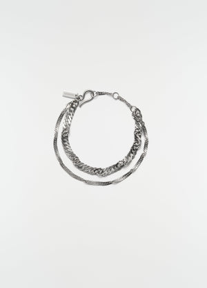 Twisted chain rhodium-plated silver bracelet by lemaire flat lay on white background with lemaire tag detail