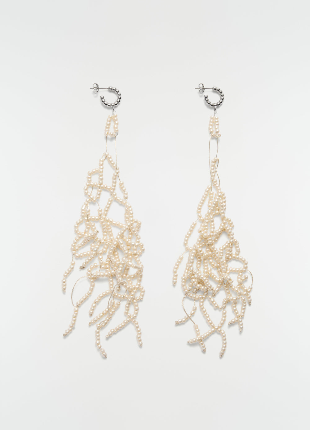Glass bead tassel earrings in cream and silver metal by LEMAIRE on plain white background