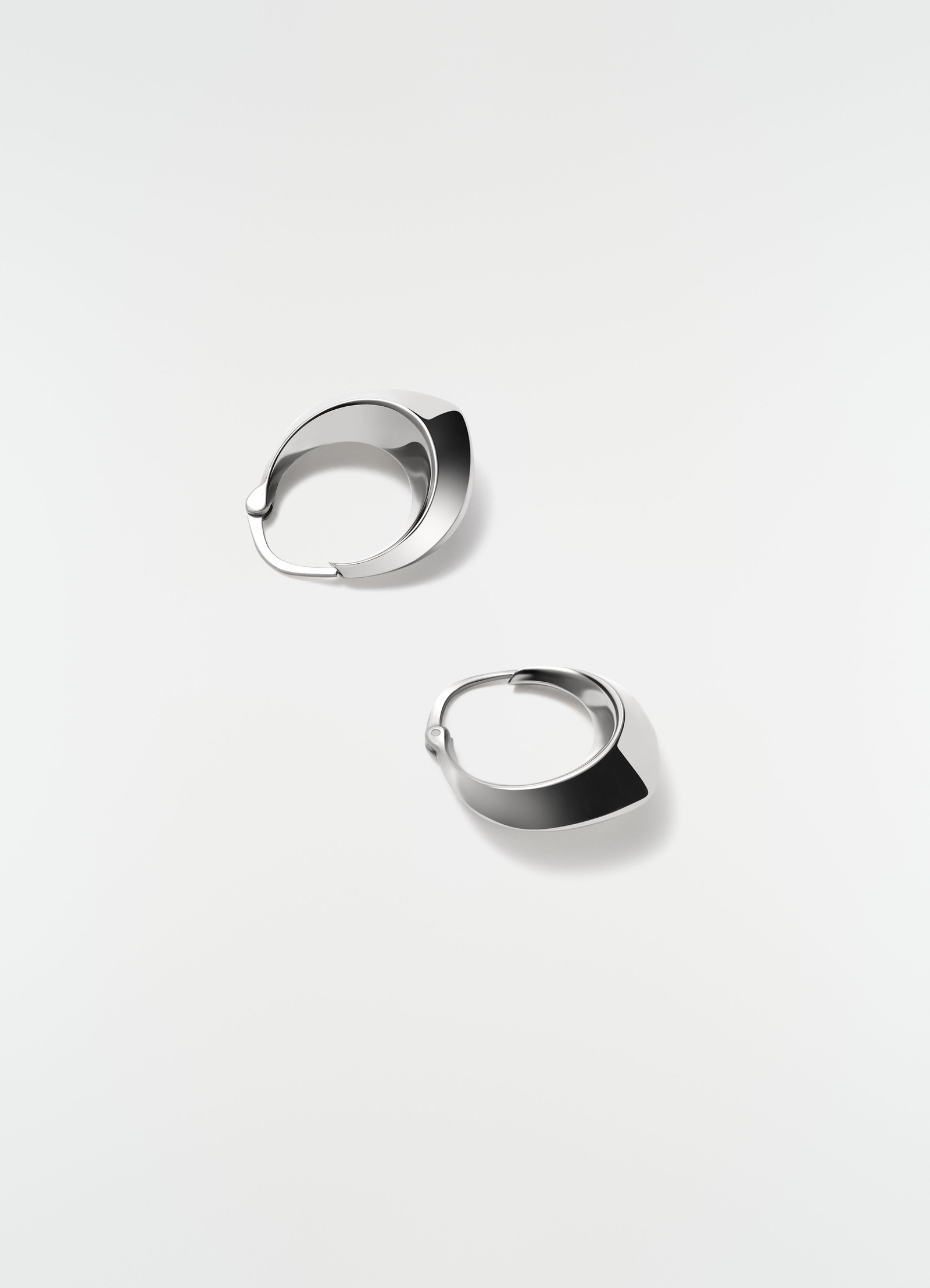Drop edge hoop earrings in rhodium-plated silver by lemaire styled on plain white background close-up.