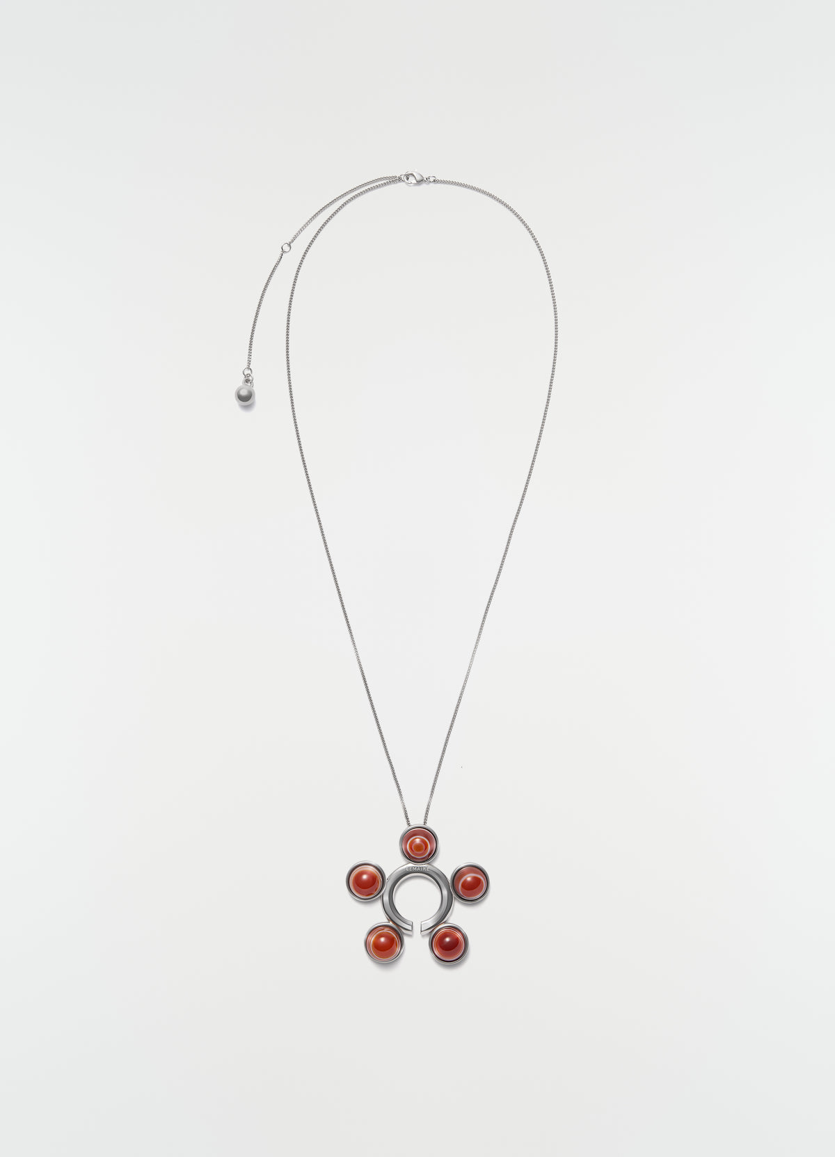 Garment jewel and necklace in silver-tone brass with red agates by LEMAIRE, on plain white background