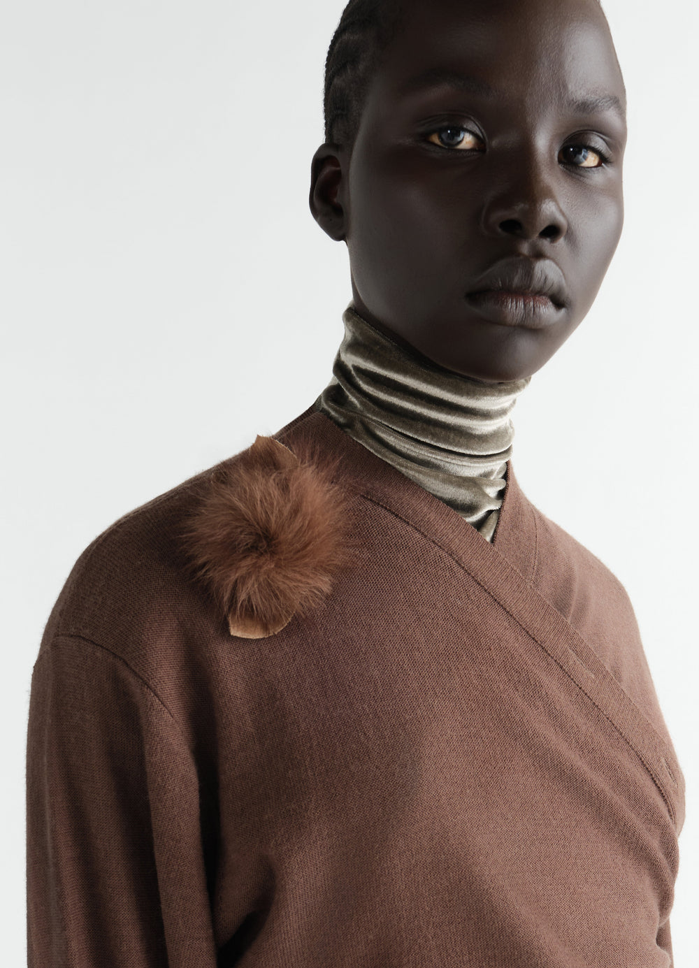 Fuzzy rose brooch in brown lambskin shearling worn on brown top by model LEMAIRE close-up front