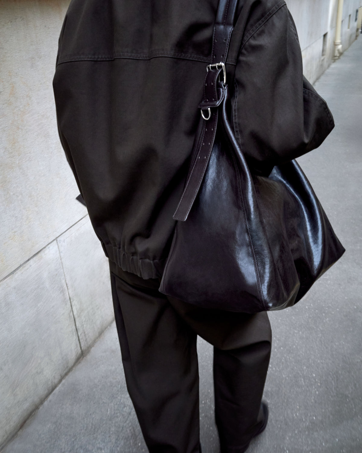 Black leather bag in Brown cotton fabric, model shot, Back view Loose fit pants