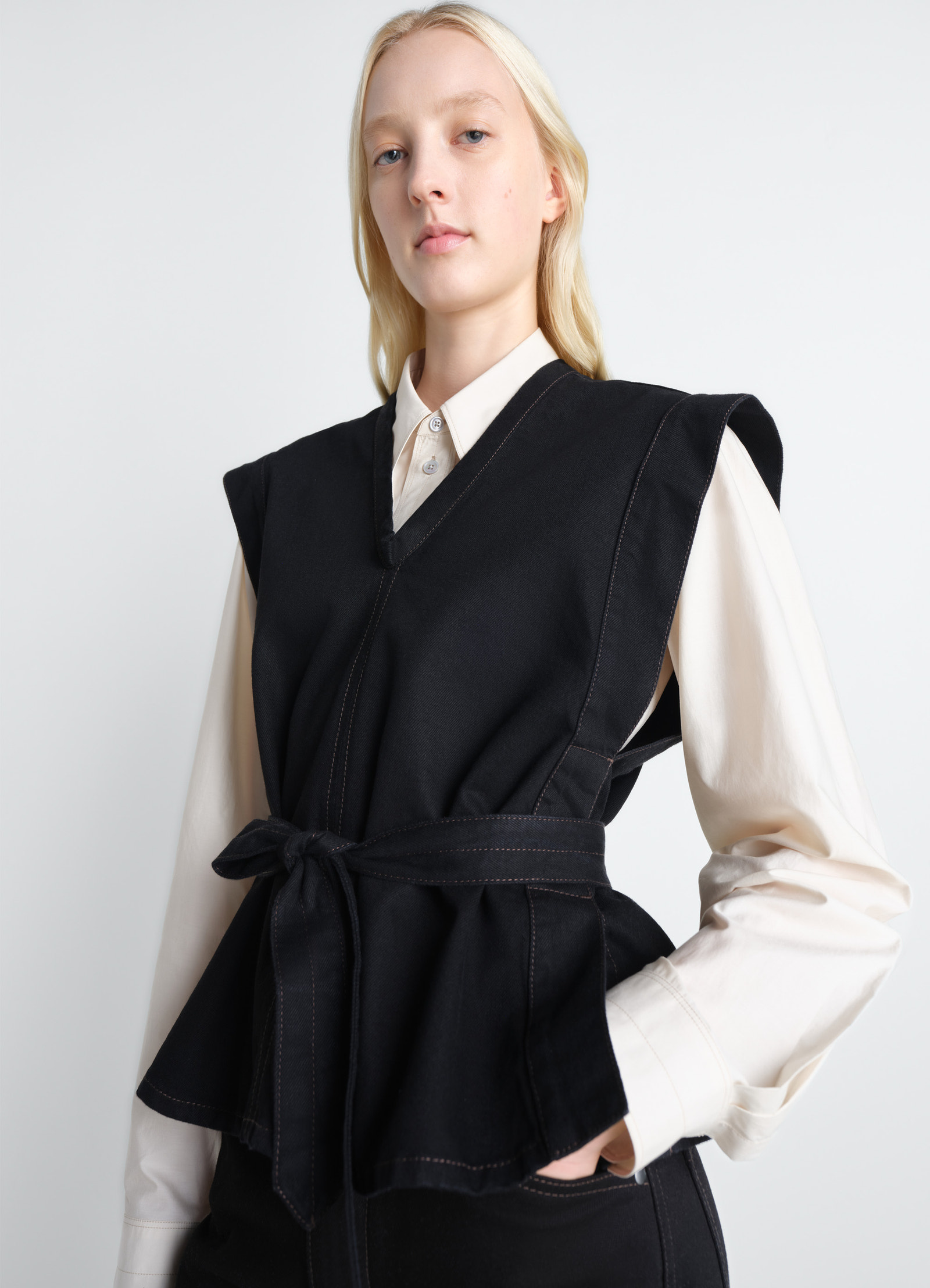 Lemaire chasuble in deep black denim, model shot, front side view v-neck, removable belt