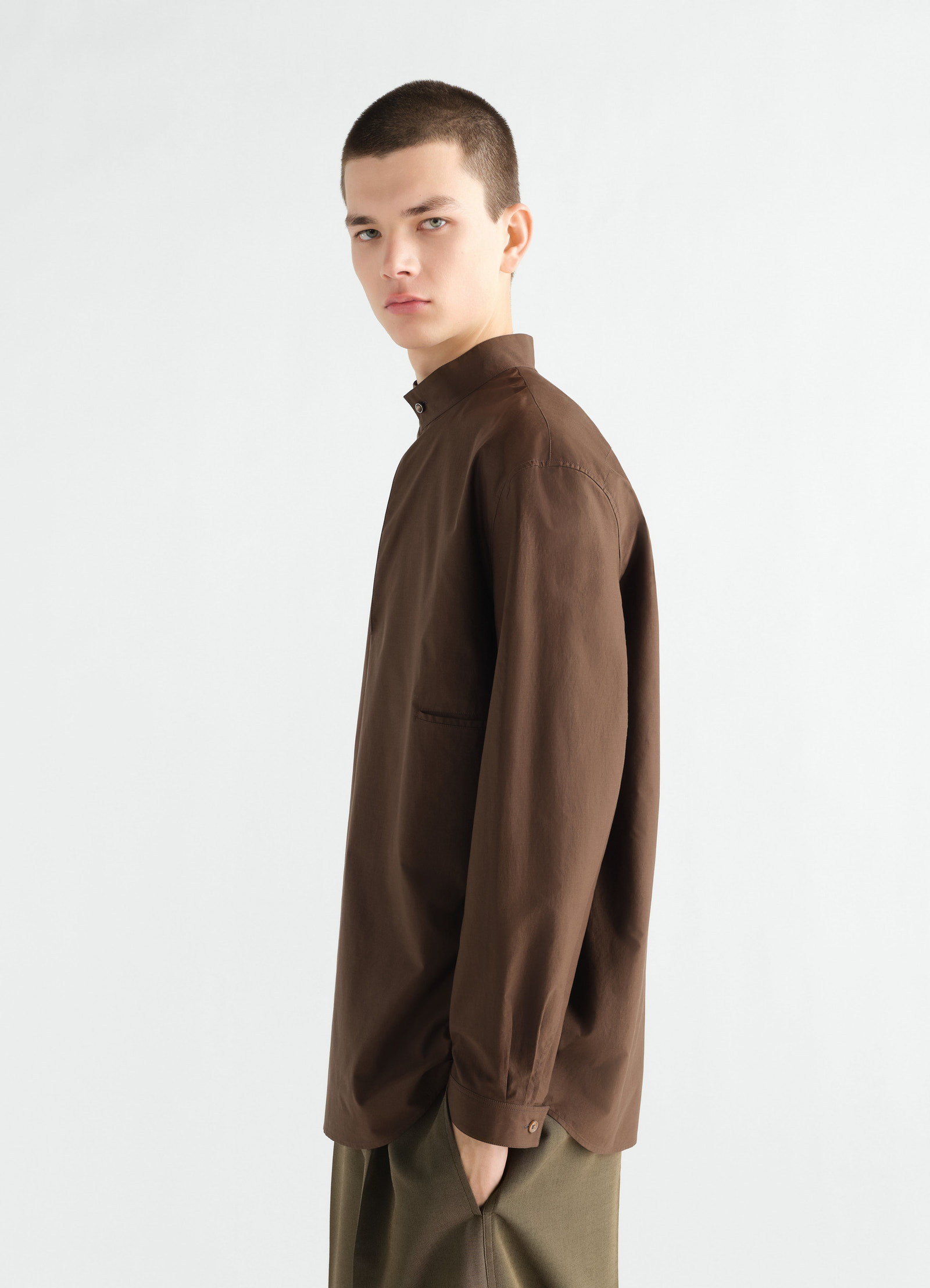 Sailor top in washed brown cotton silk blend by lemaire worn by model side view with high collar and buttoned cuffs