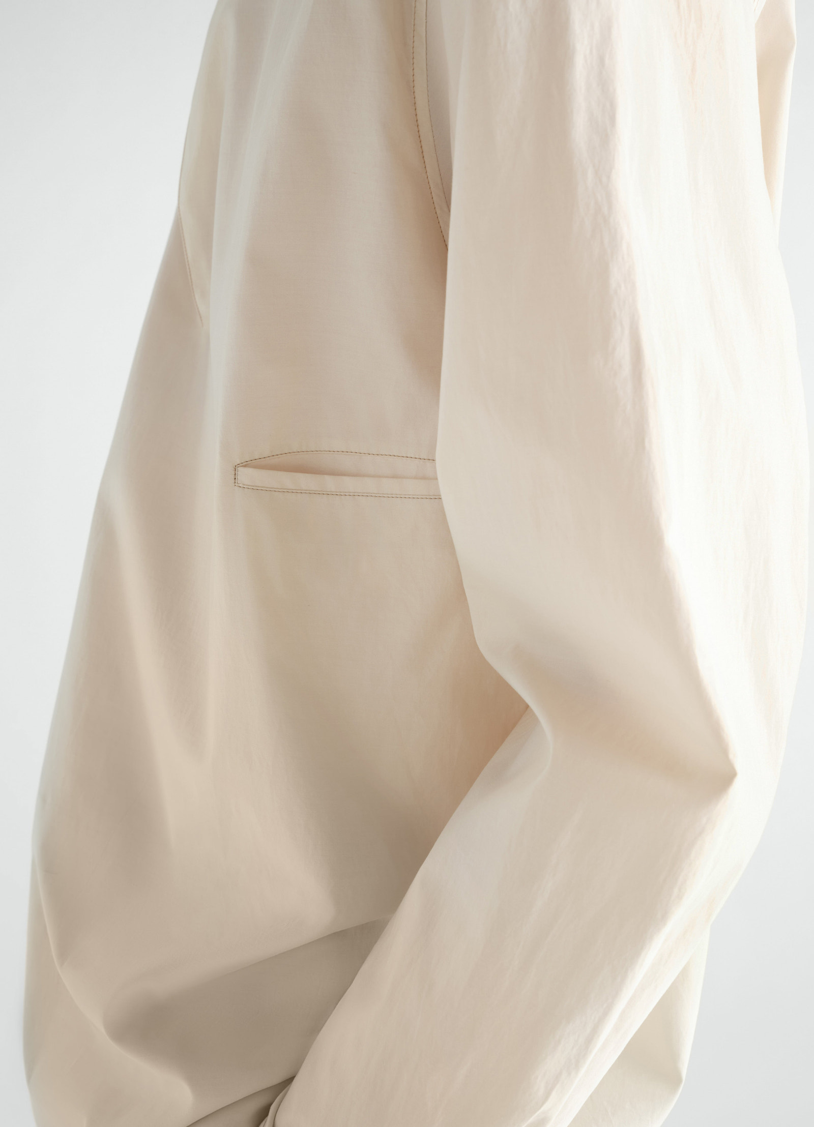 Sailor top in beige washed cotton and silk blend by lemaire close-up detail of side pocket and sleeve worn by a model
