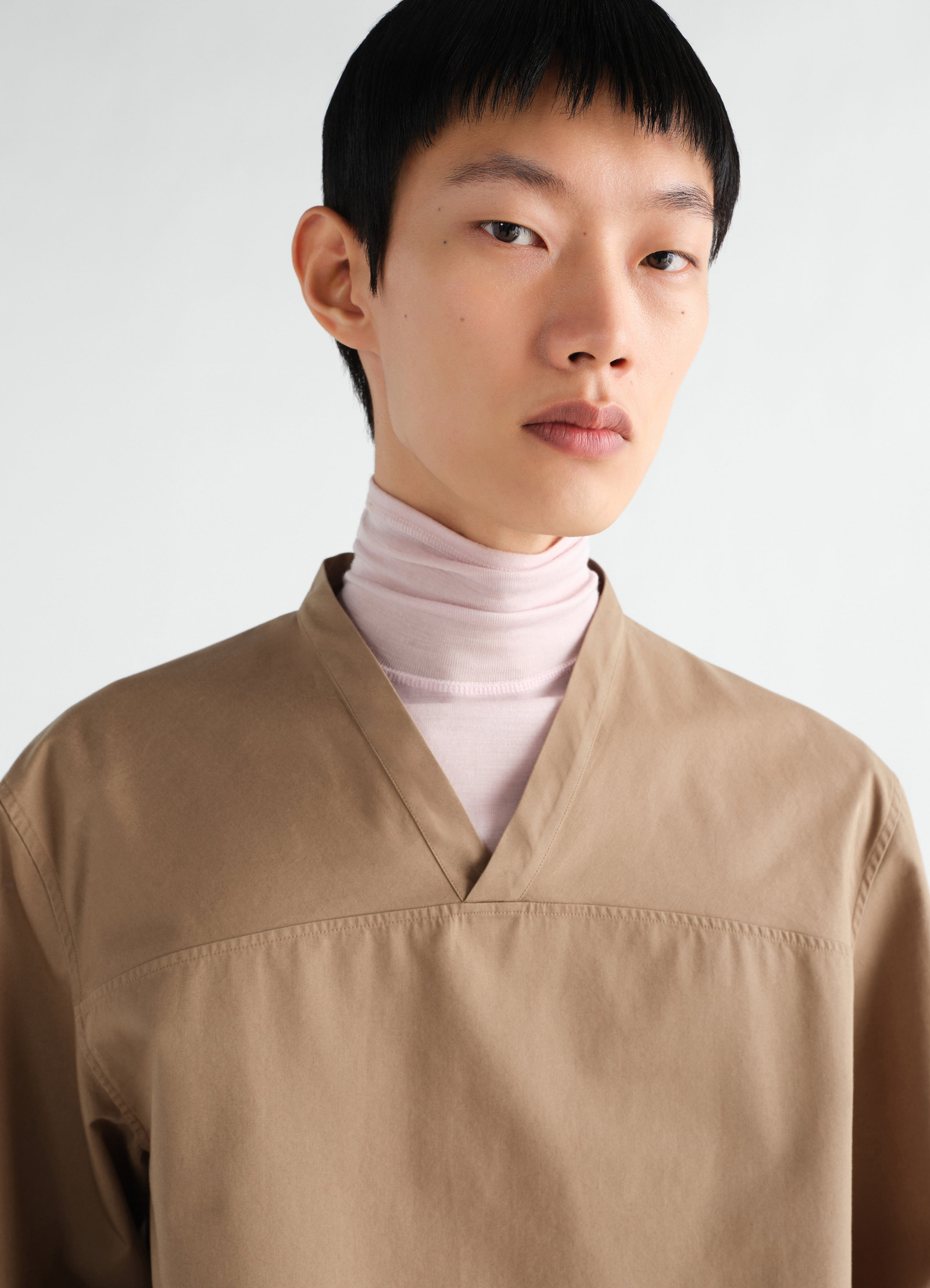 V-neck light brown cotton twill top worn by model with pale pink turtleneck lemaire front close-up