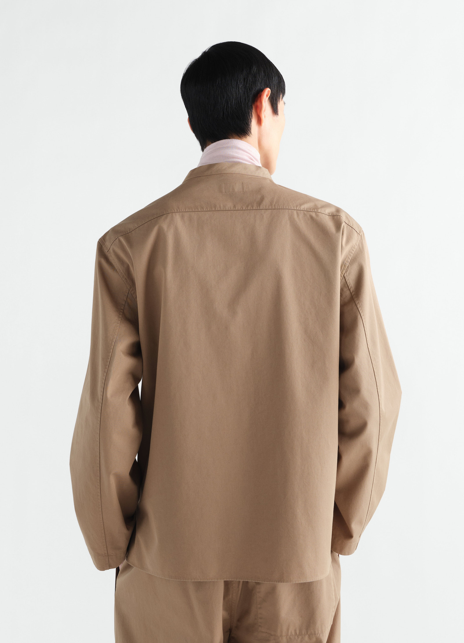 V-neck light brown cotton twill top by lemaire worn by model shown from back with long sleeves