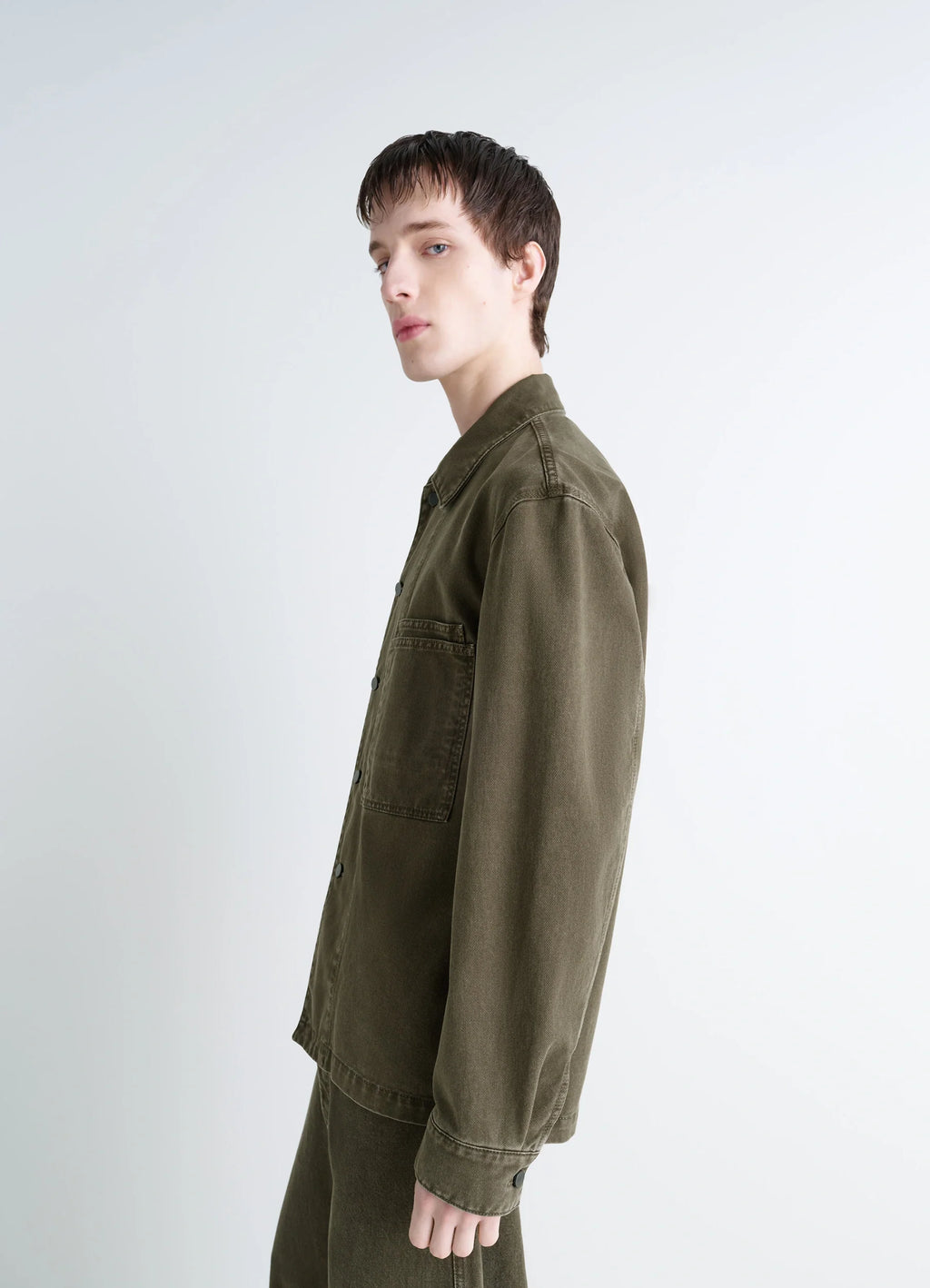 Lemaire Workwear Overshirt in Garment Dyed Snowy Denim, model shot, side profile view long sleeves, button cuffs