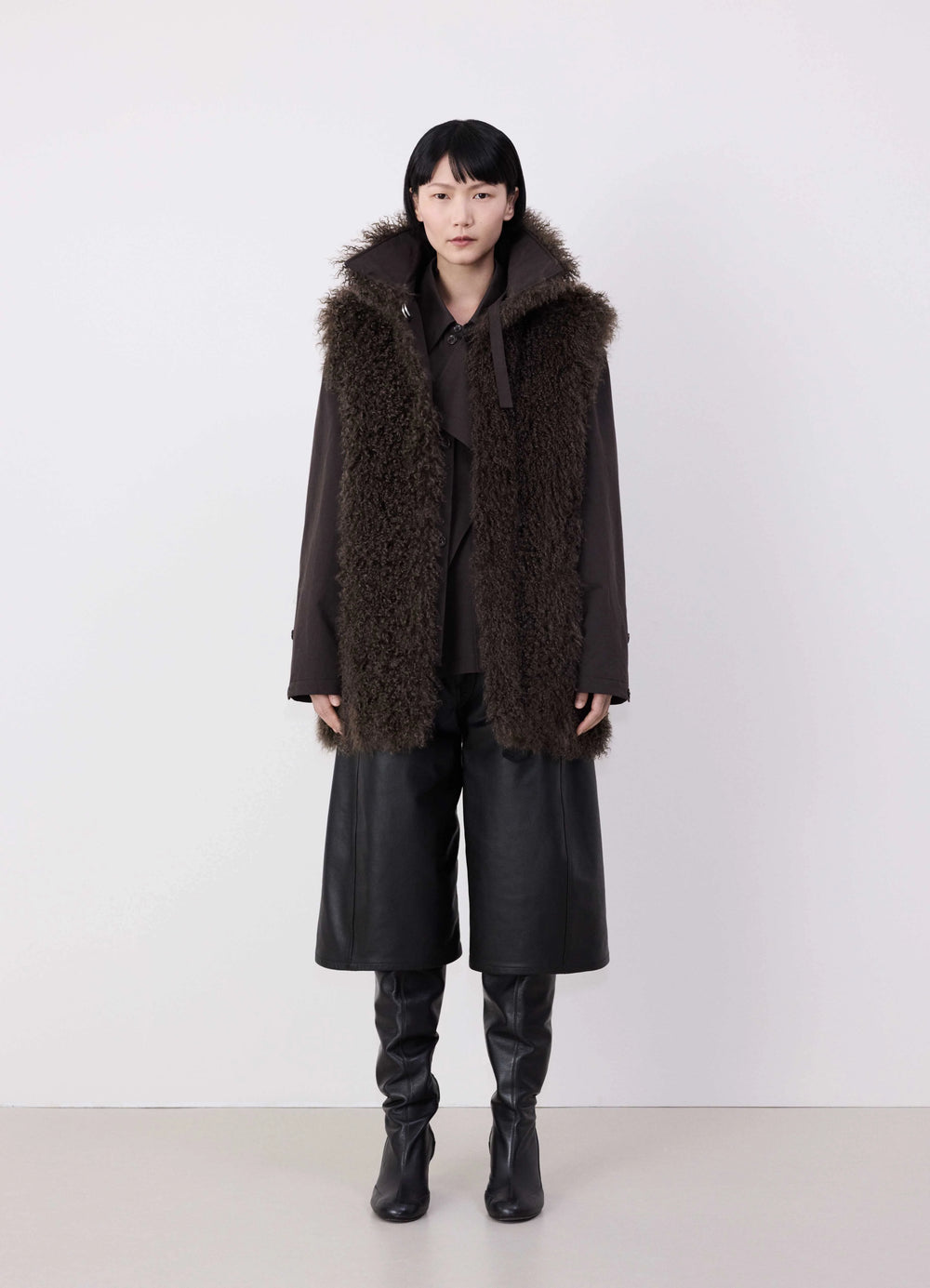 Lemaire Reversible Belted Long Shea in Dark Shearling and Cotton Twill, model shot, front view with hood full length worn by