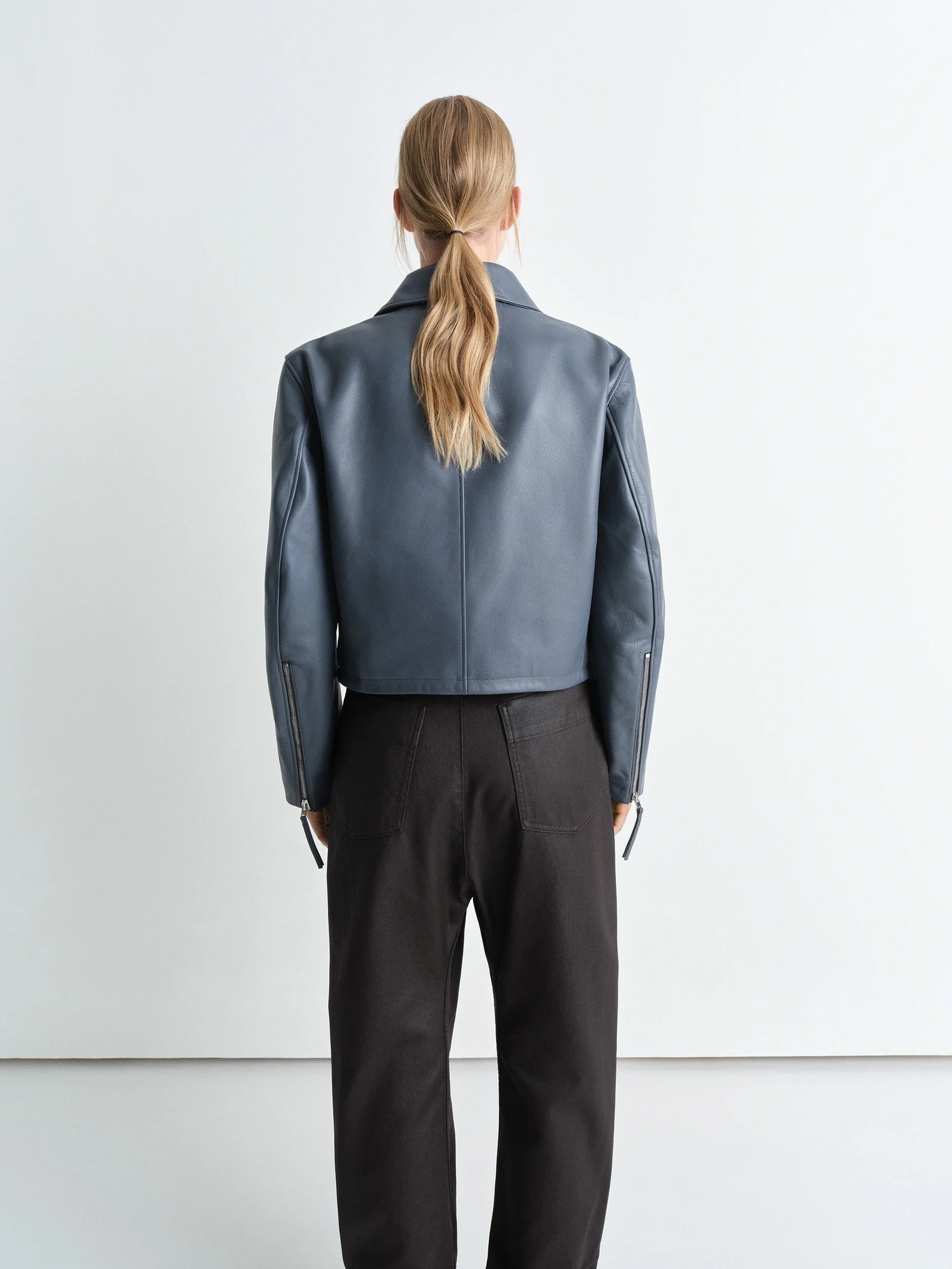 Boxy cropped jacket in heavy cow leather, model shot, back view zippered sleeve cuffs