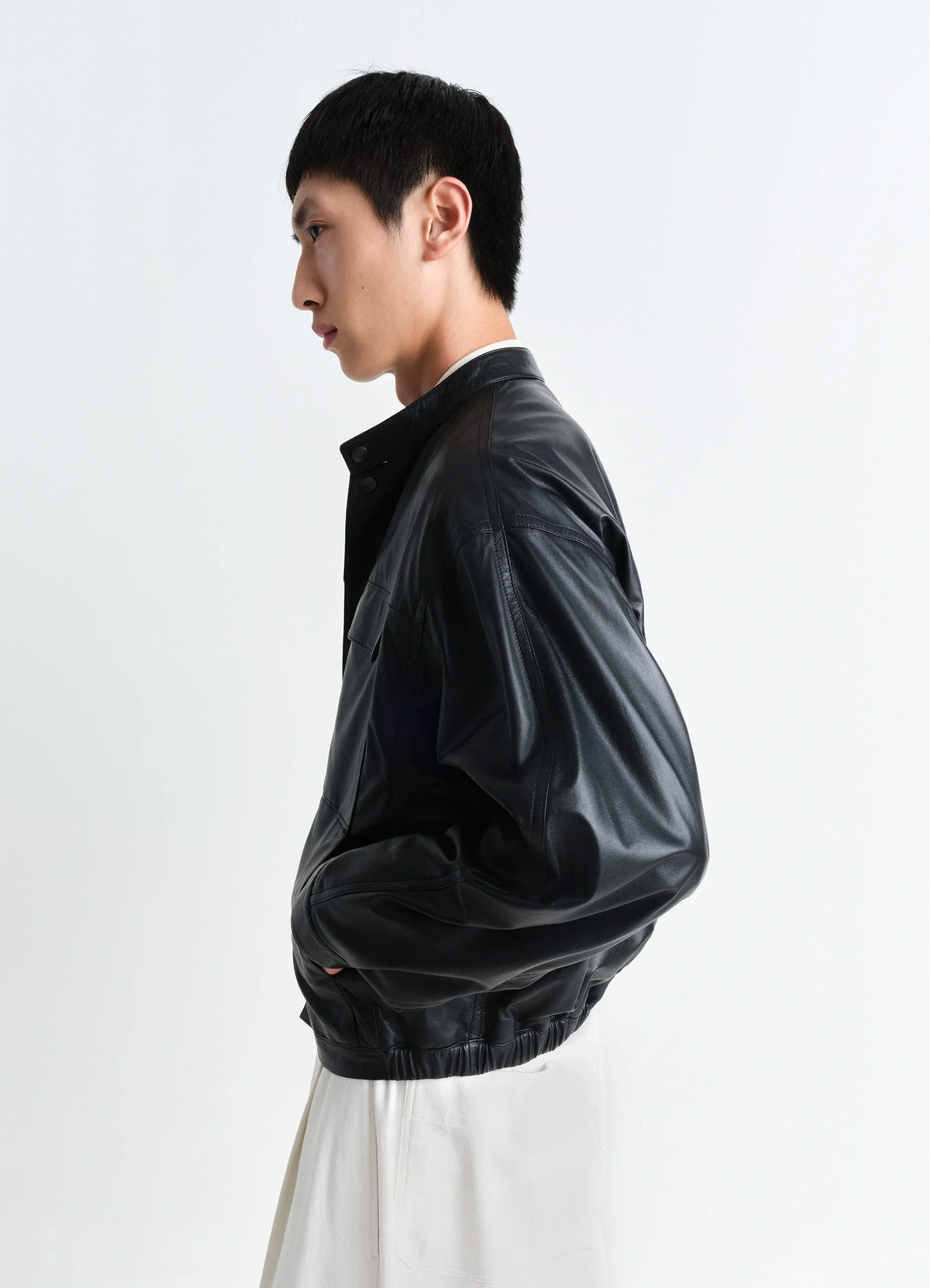 Soft boxy blouson in black lamb leather, model shot, profile view elastic hem, pocket detail