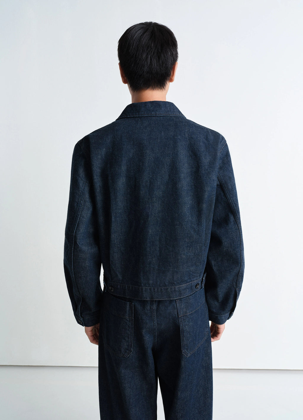 Lemaire Trucker Jacket in Deep Indigo Heavy Denim, model shot, back view straight hem buttoned cuffs