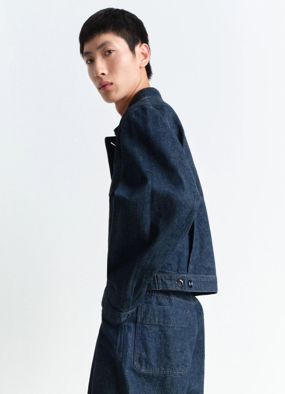 Lemaire Trucker Jacket in Deep Indigo Heavy Denim, model shot, side view adjustable back strap