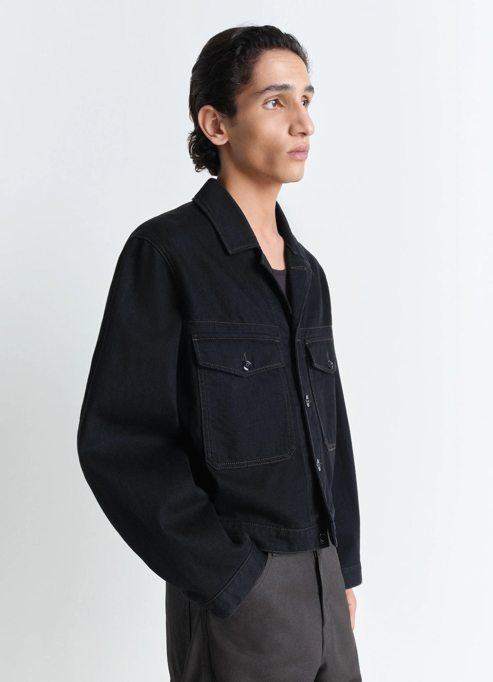 Lemaire Trucker Jacket in Deep Black Heavy Denim, model shot, three-quarter view patch pockets, relaxed fit