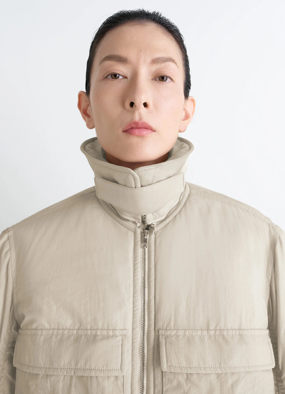 Lemaire Short Bomber in Beige Lightweight Nylon, model shot, close-up front view high collar, flap pockets