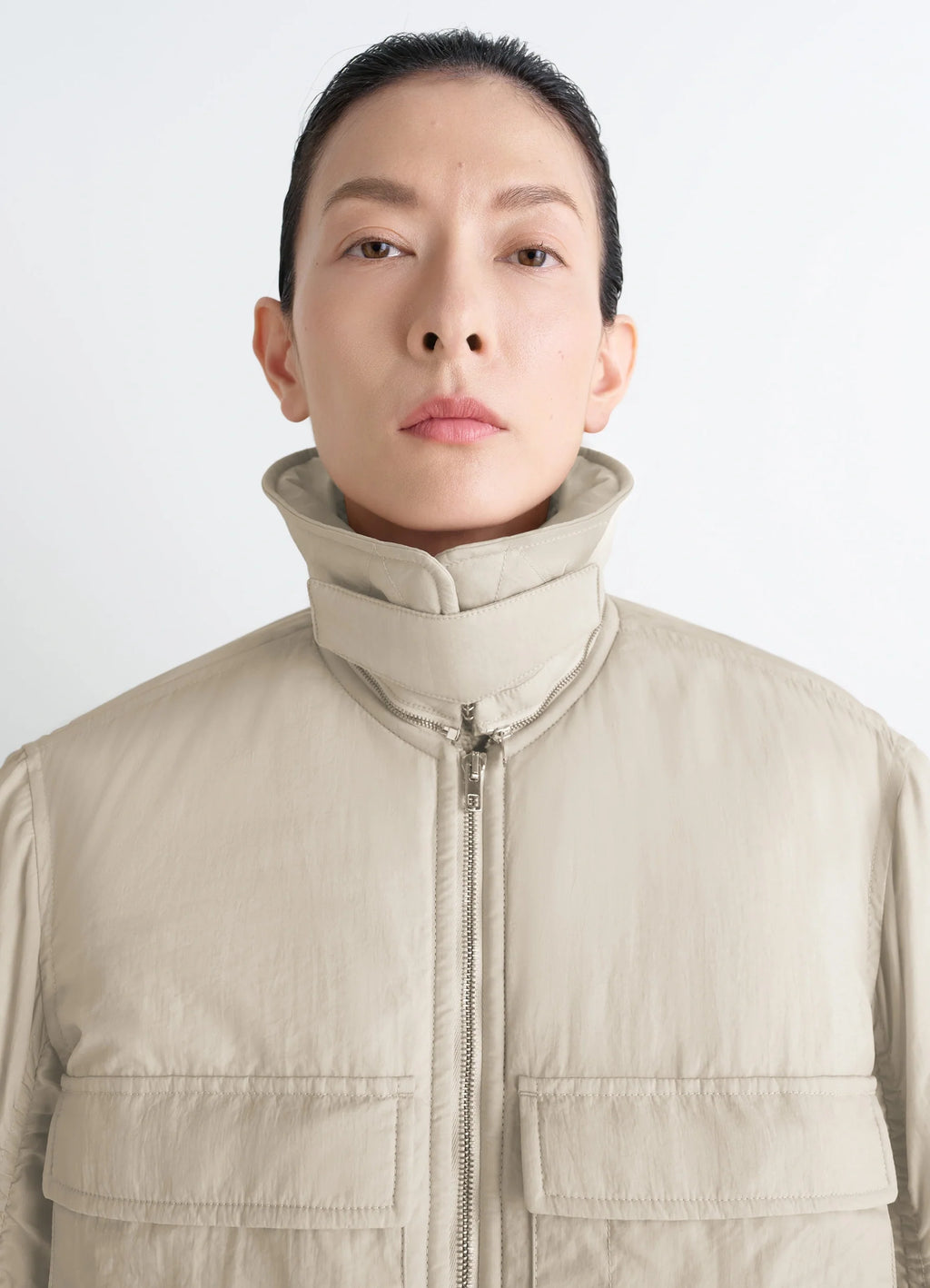 Lemaire Short Bomber in Beige Lightweight Nylon, model shot, close-up front view high collar, flap pockets