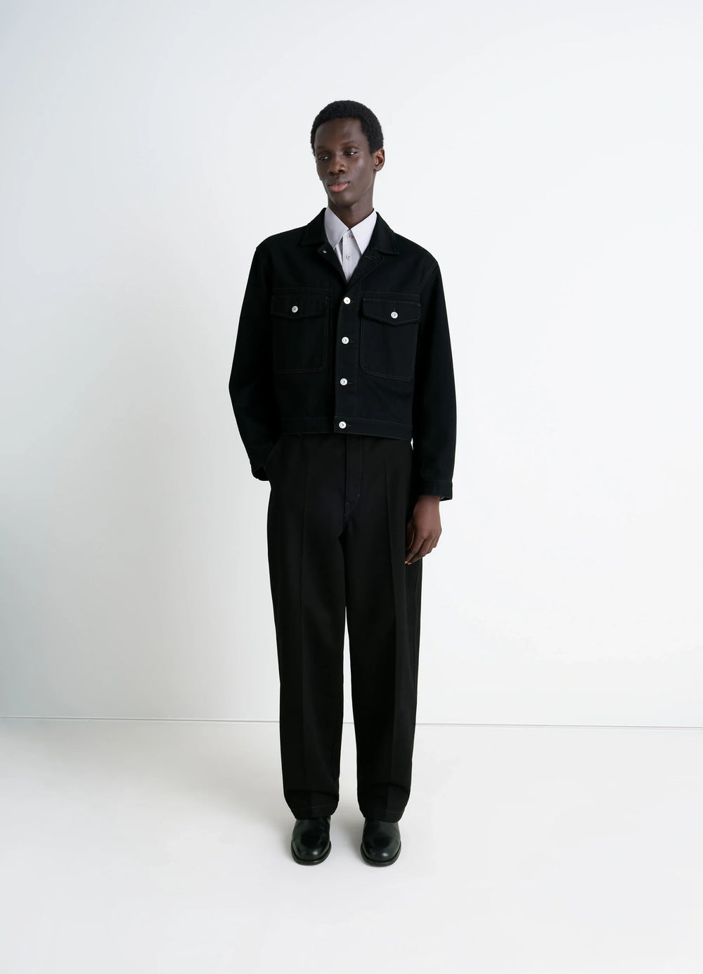 Lemaire Trucker Jacket in Deep Black Thick Denim, model shot, full body front view boxy fit, button closure