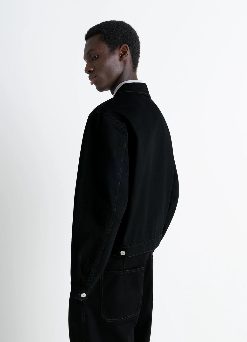 Lemaire Trucker Jacket in Deep Black Thick Denim, model shot, back side view adjustable cuffs