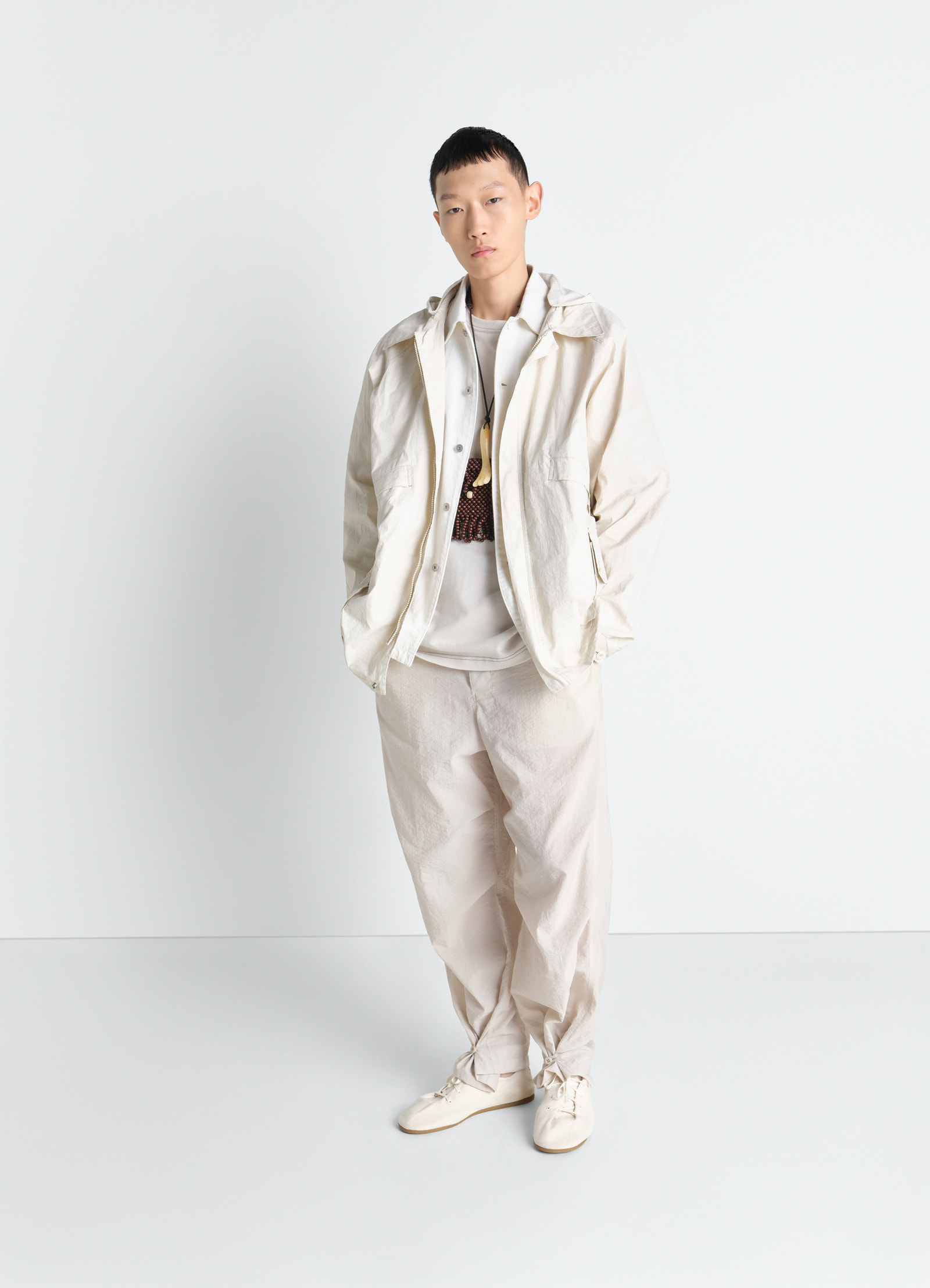 Lemaire rain jacket in coated technical linen, model shot, three-quarter view neutral color worn by model