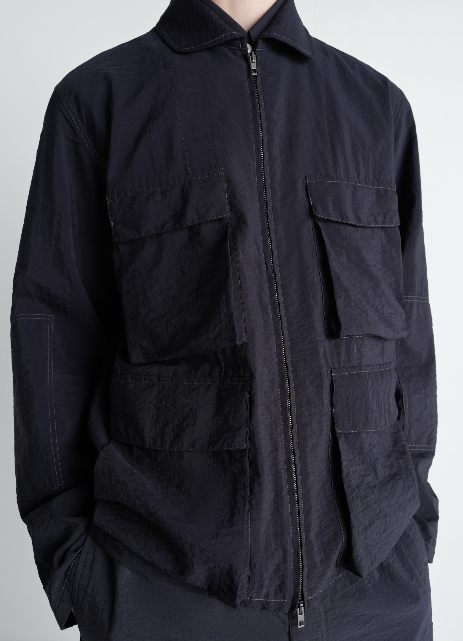 3d pocket jacket in washed technical cotton, model shot, close-up view textured fabric, zip closure