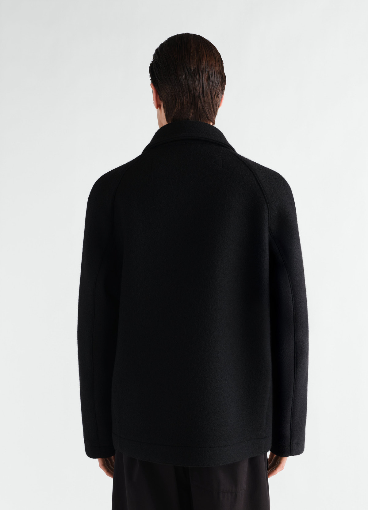 Utility jacket in black heavy wool cloth lemaire worn by a model back view on plain background