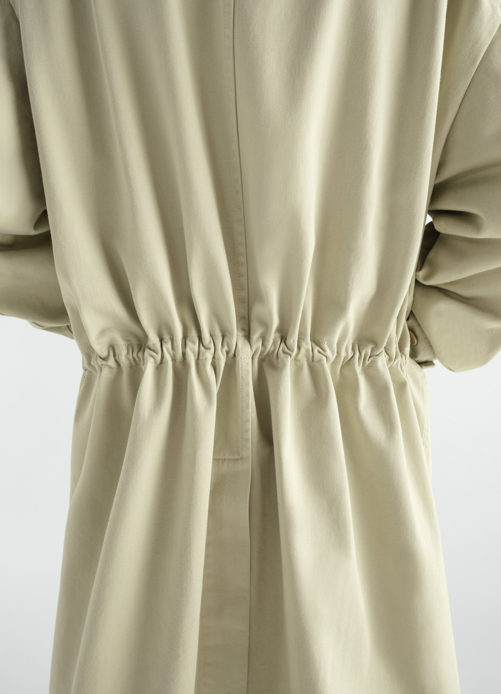 Military parka in beige heavy cotton satin with gathered waist detail worn by model lemaire