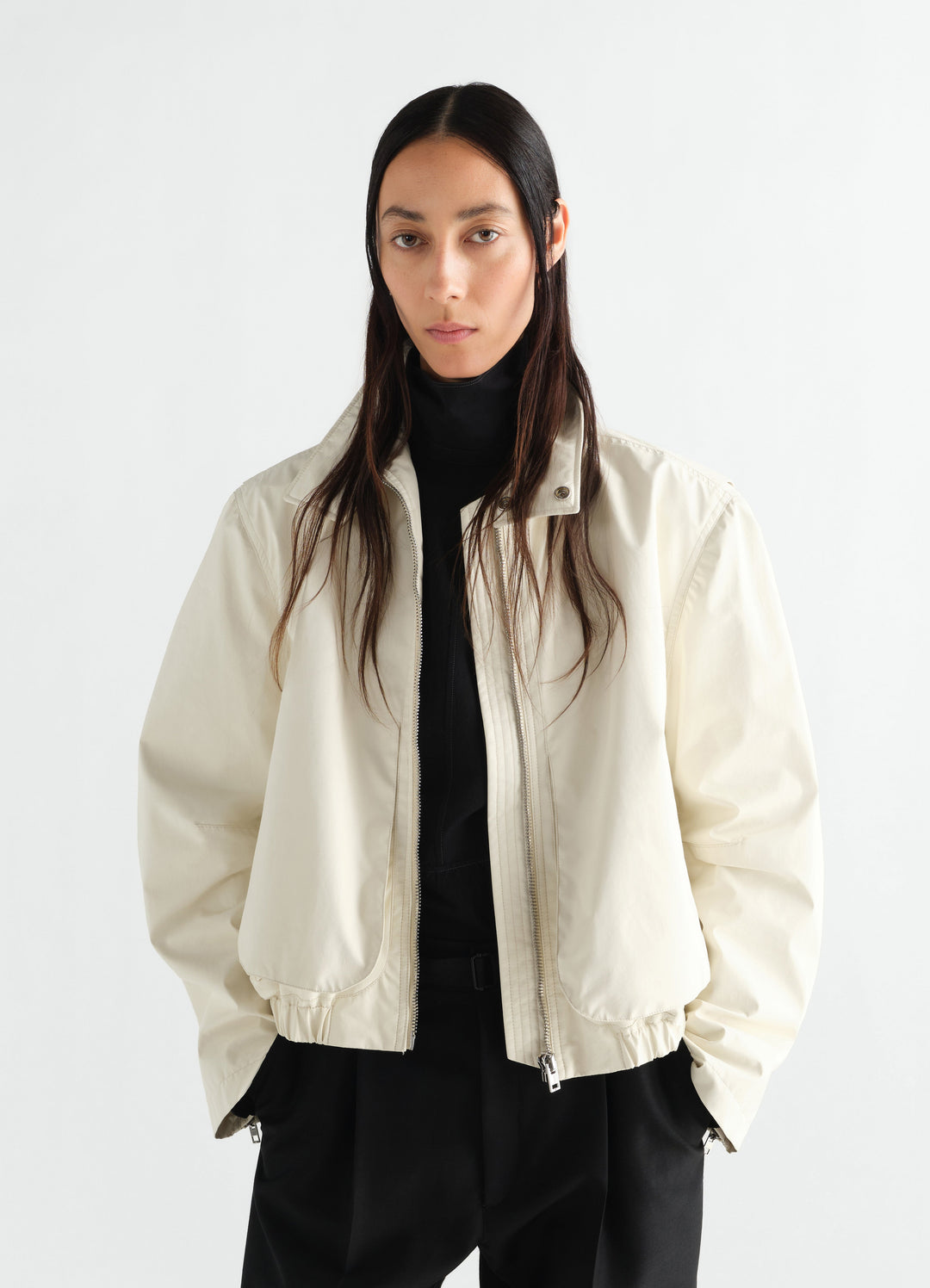 Zipped blouson in off-white waterproof cotton LEMAIRE worn by model front view with black outfit underneath