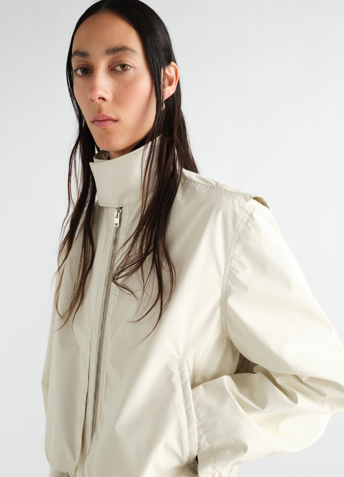 Zipped waterproof cotton blouson in beige by lemaire worn by model front view with high collar