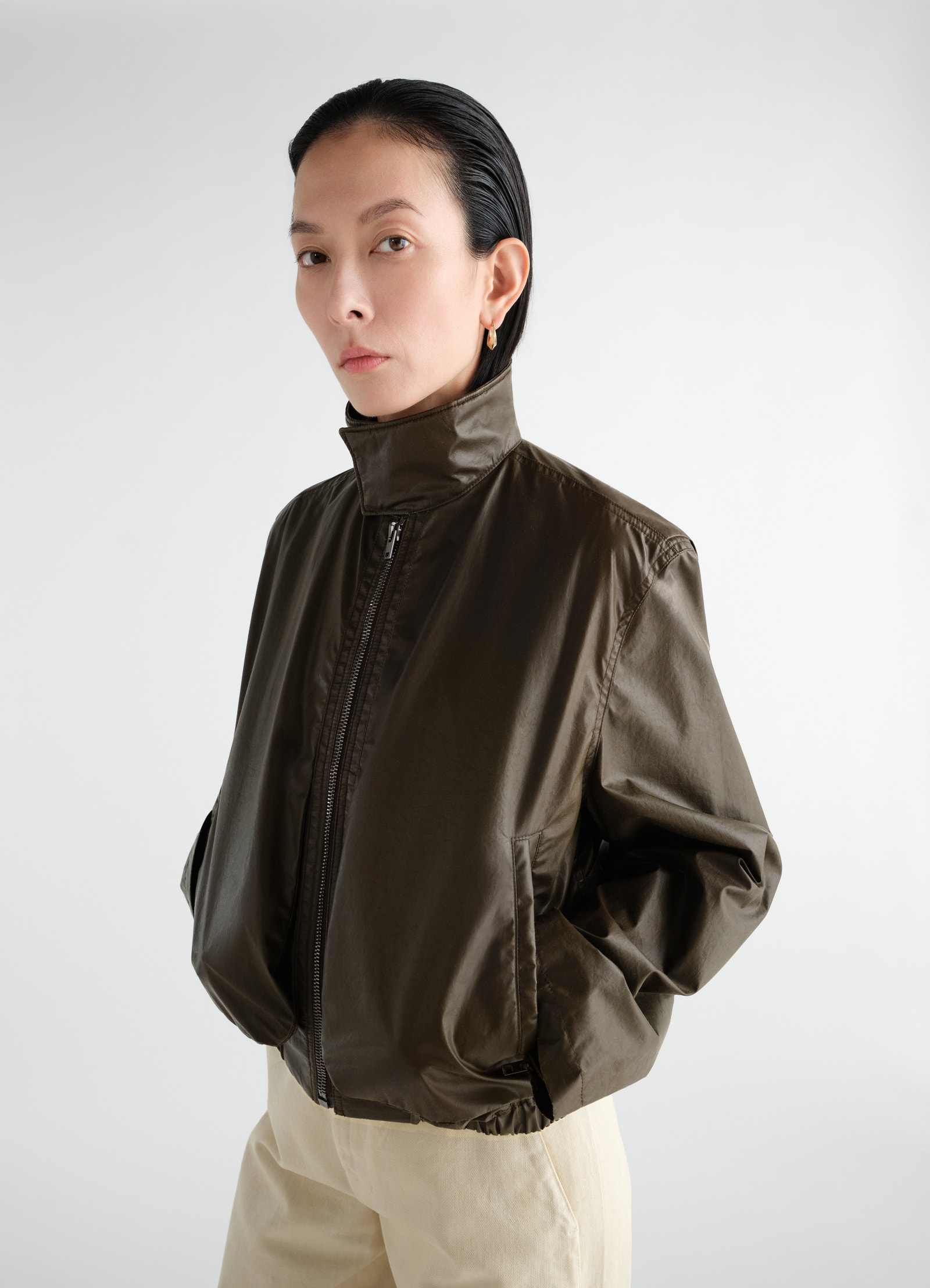 Zipped blouson in dark olive waterproof cotton by lemaire worn by a model with high collar and front pockets