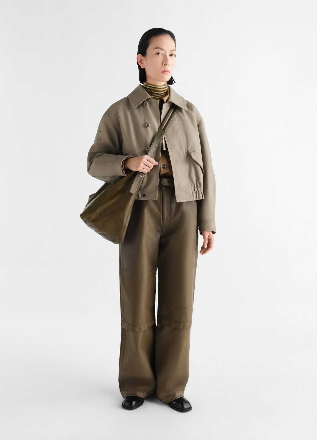 Short blouson in heavy cotton twill beige worn by model with matching pants and olive leather bag lemaire front view