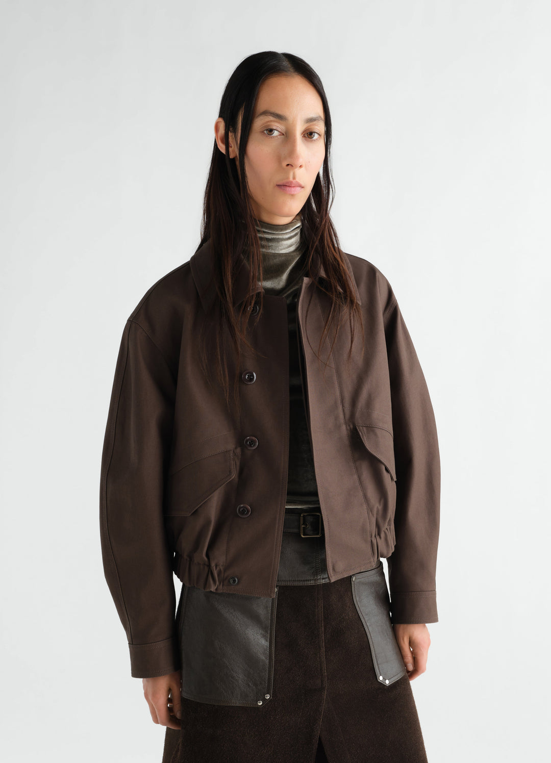 Short brown heavy cotton twill blouson jacket by LEMAIRE worn by model front view with button closure and flap pockets