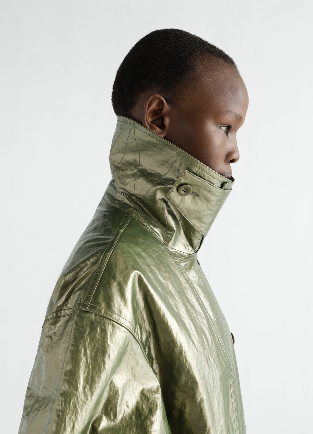 Trench coat in water-repellent shiny coated linen olive green worn by model side view LEMAIRE