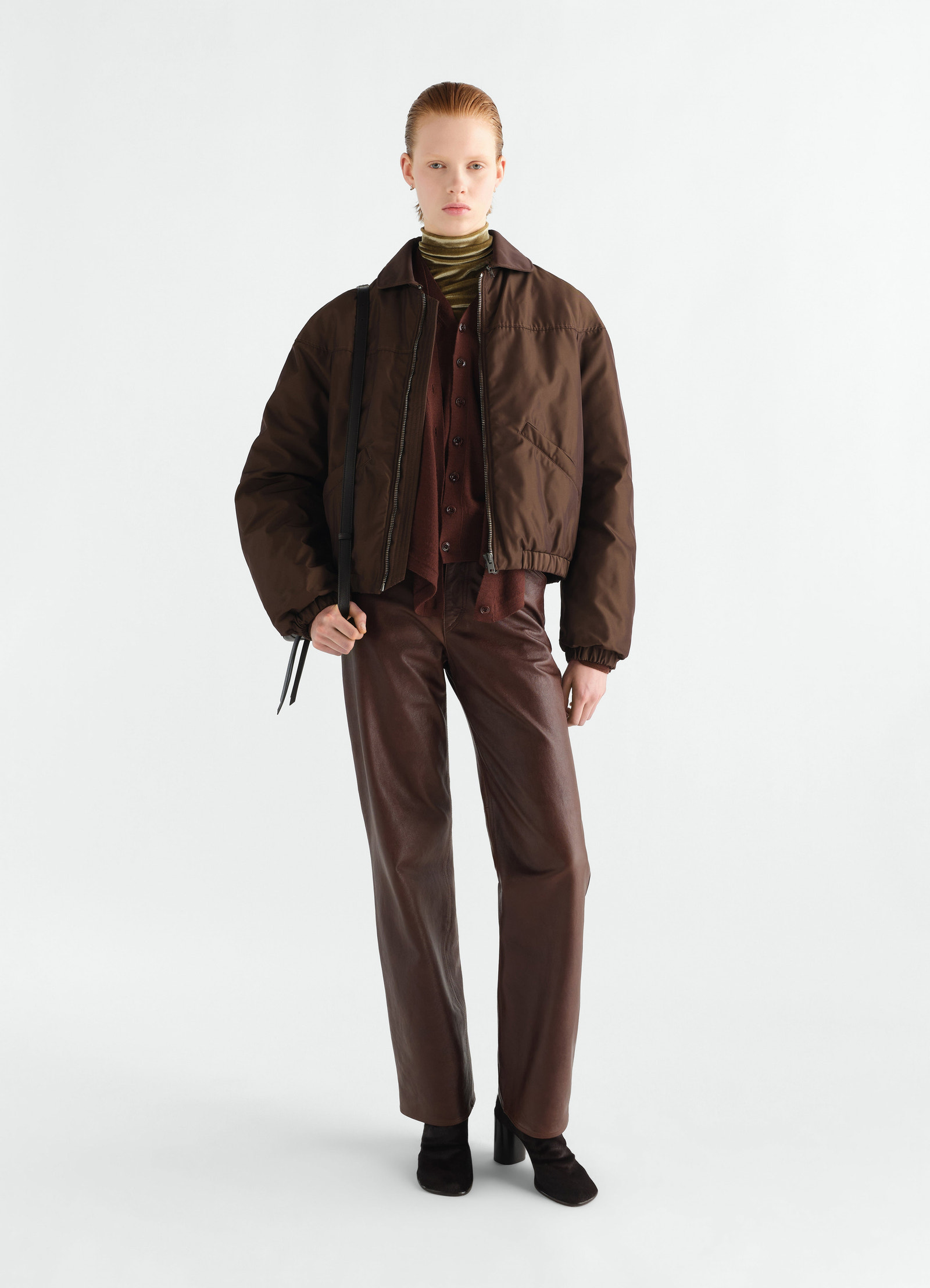 Quilted dark brown water-repellent canvas blouson worn by a model styled with brown leather pants by lemaire