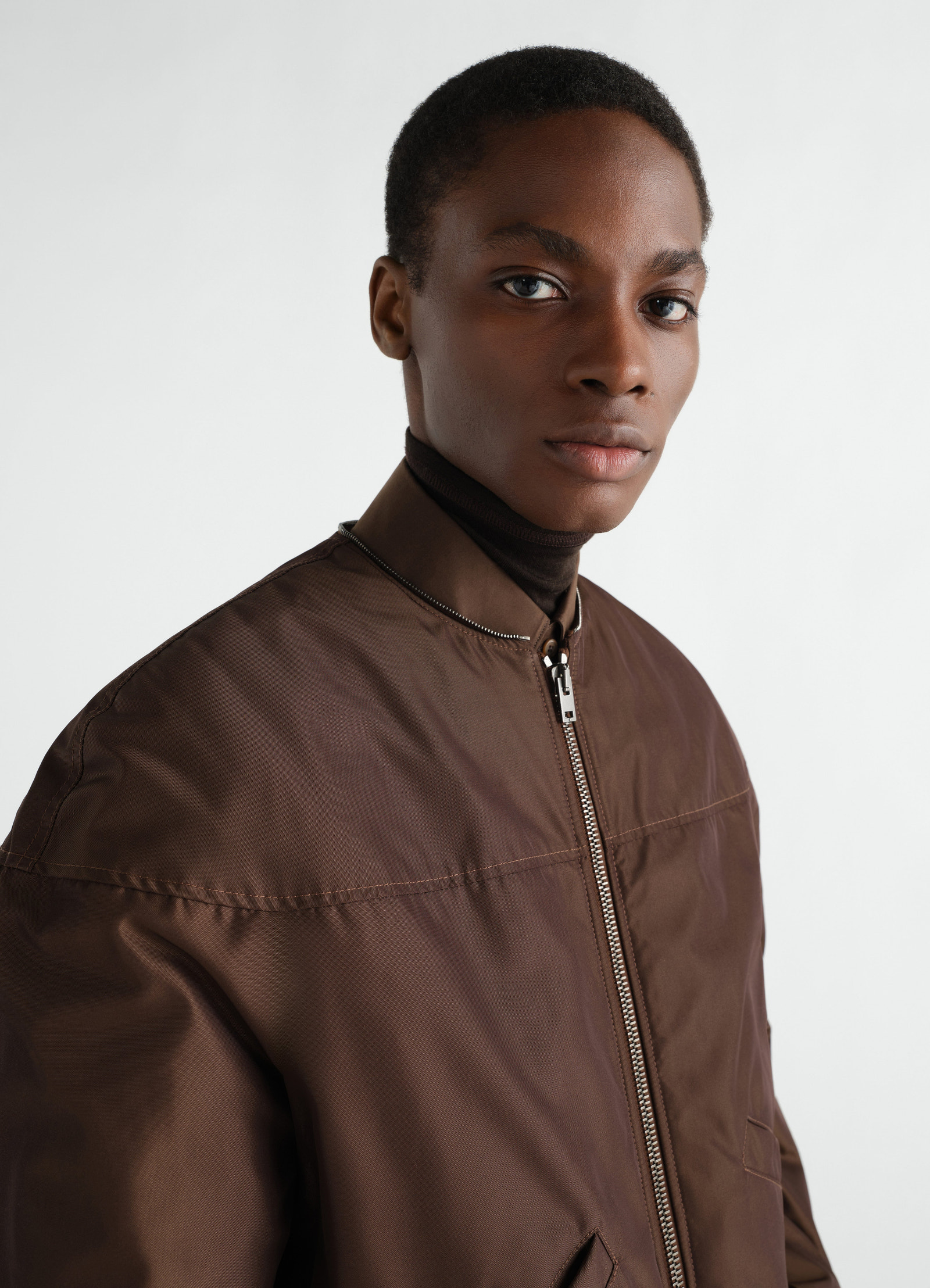 Quilted brown water-repellent canvas blouson by lemaire worn by a model front detail with zipper and pockets