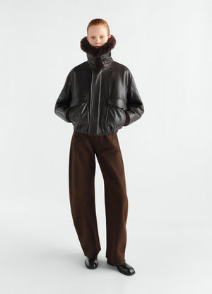 Aviator shiny black leather blouson with fur collar worn by model styled look lemaire