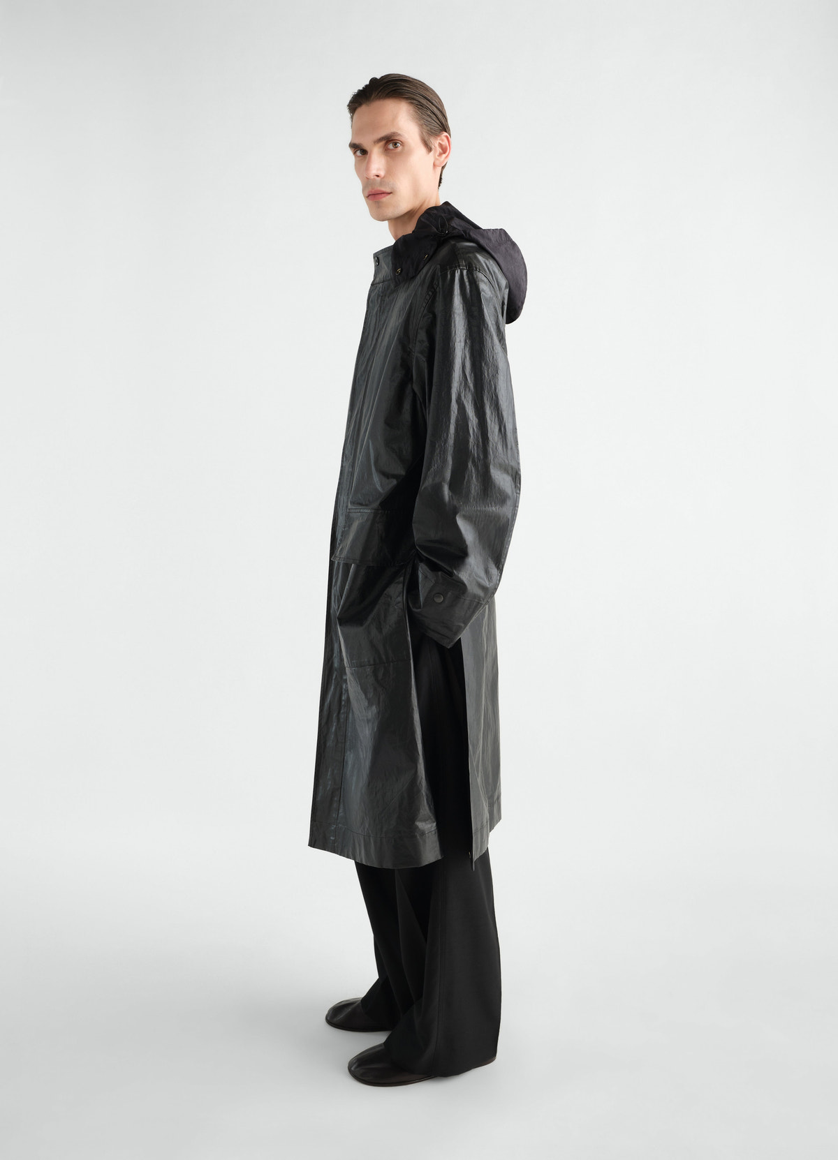 Long black coated linen cotton blend raincoat with hood by lemaire worn by model side view