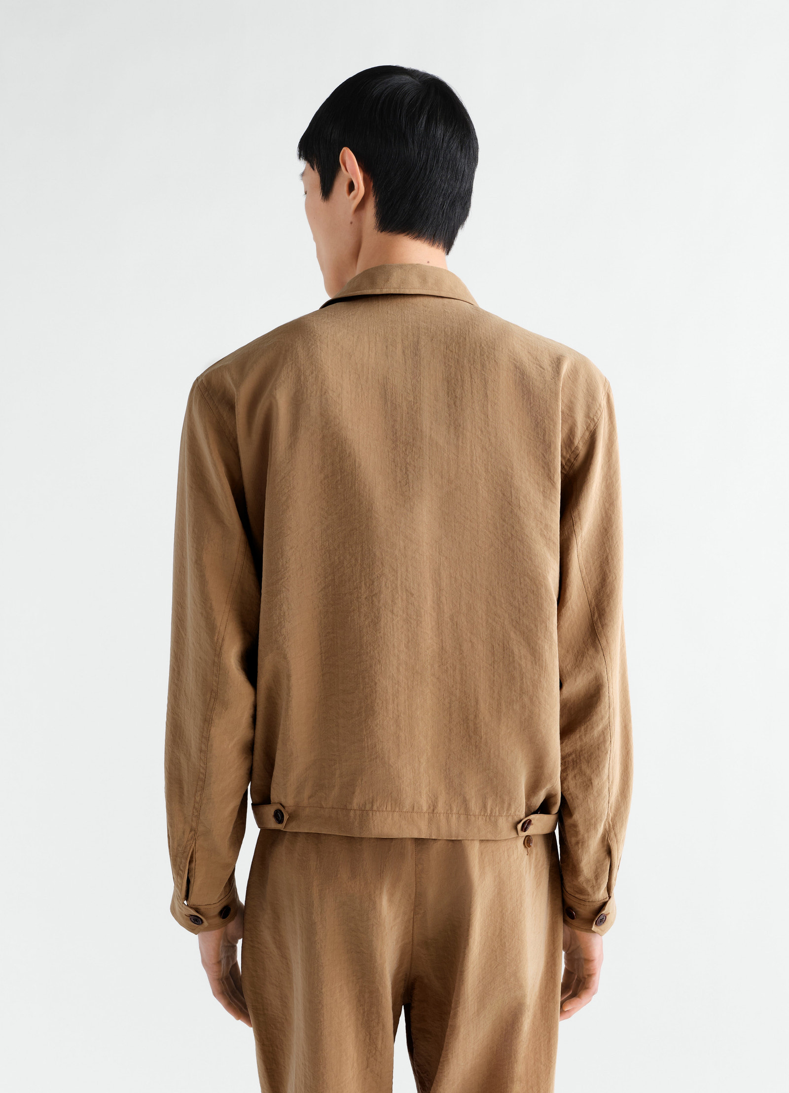 Light brown dry silk zipped blouson by lemaire worn by model, back view showing collar and cuff buttons
