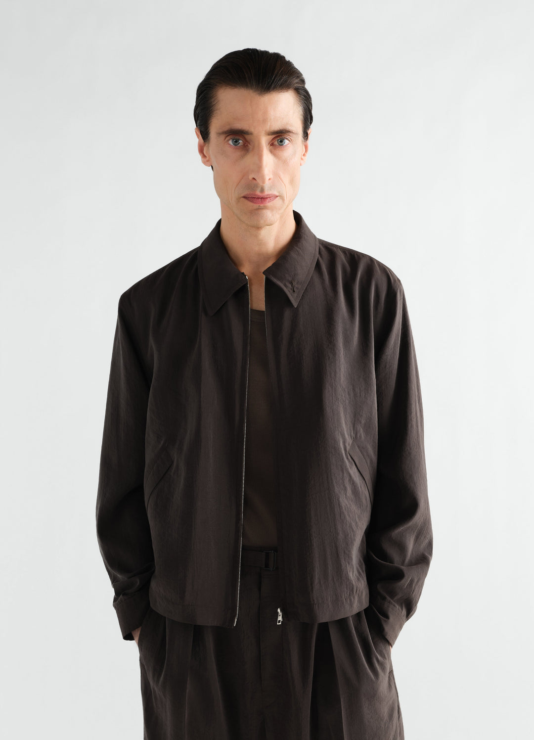 Light brown dry silk zipped blouson by LEMAIRE worn by a male model front view on white background