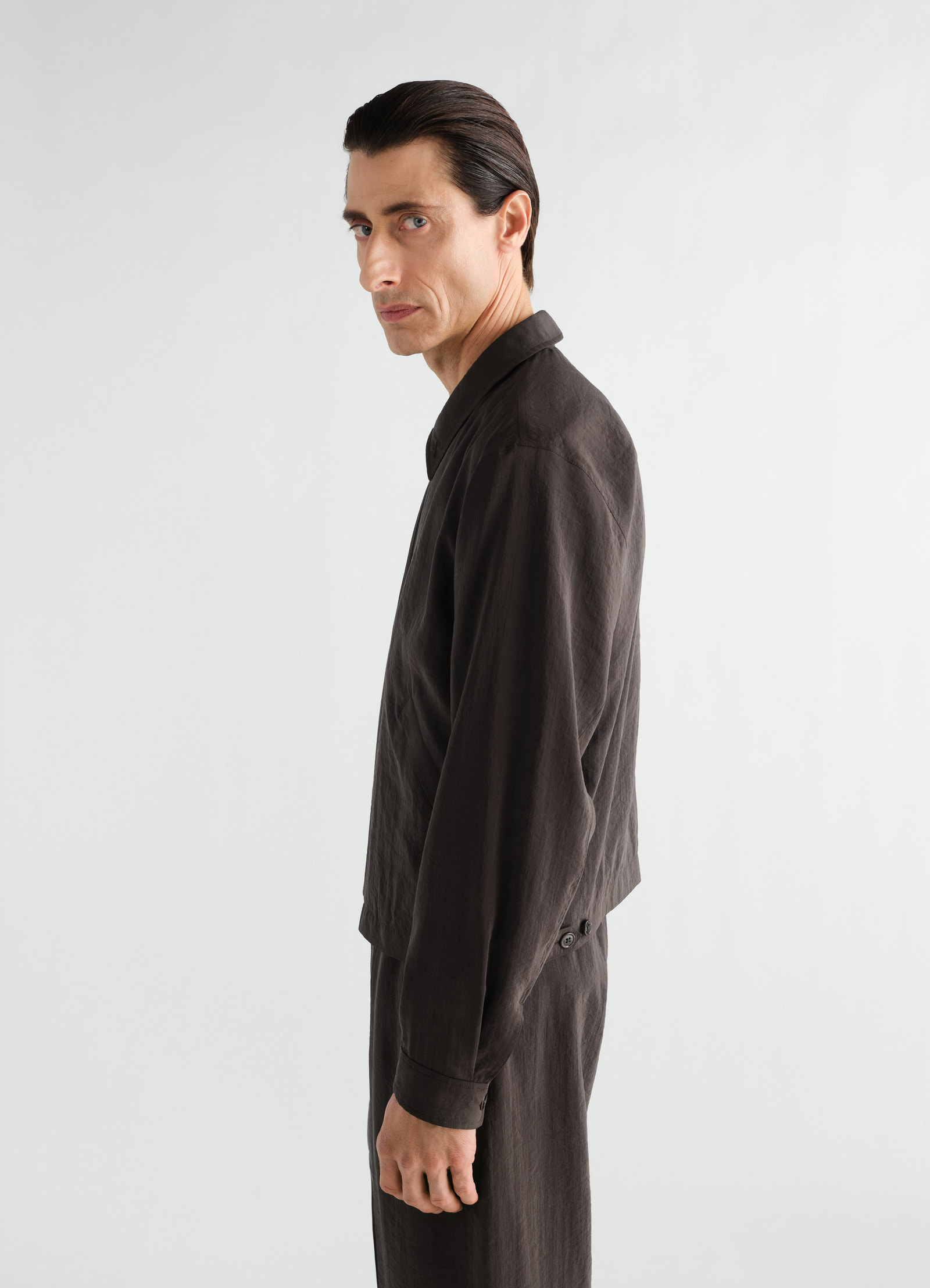 Black dry silk light zipped blouson by lemaire worn by model side view with buttoned cuffs and collar