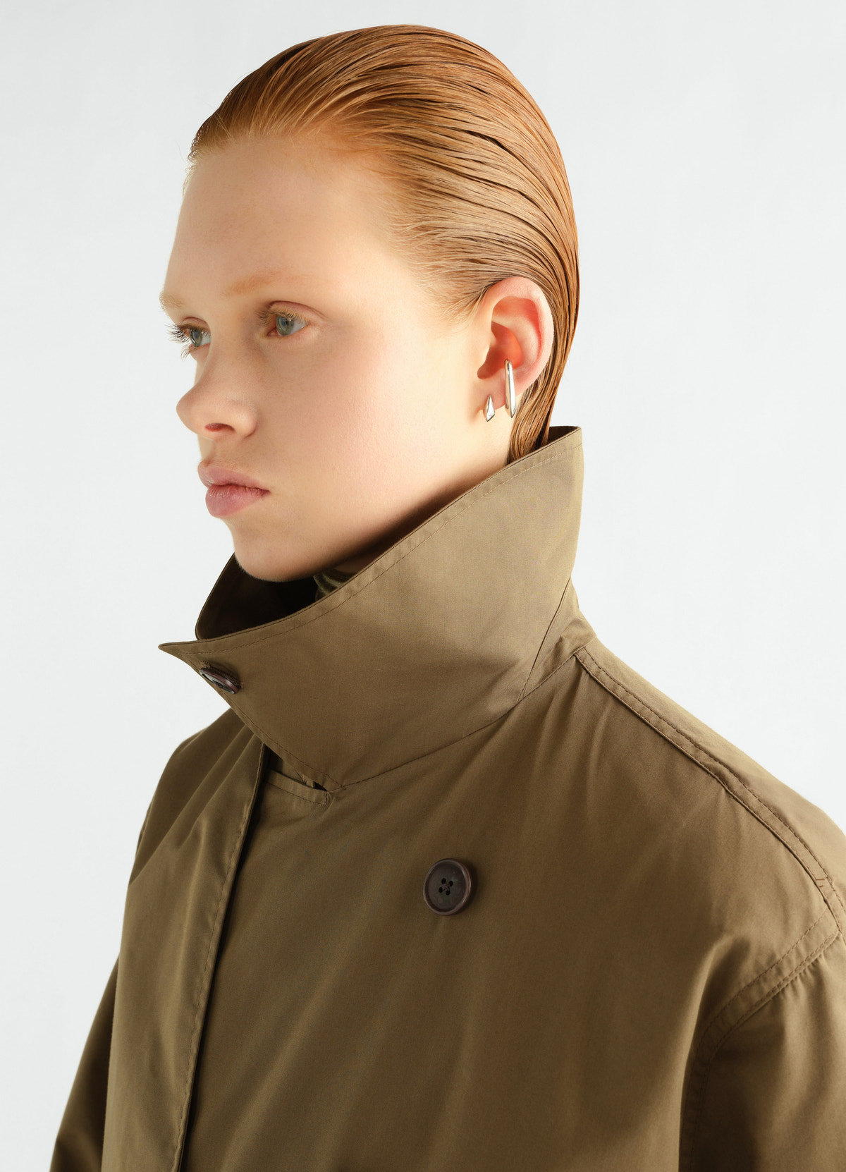 Light trench coat in water-repellent brown cotton gabardine by lemaire worn by a model side close-up detail